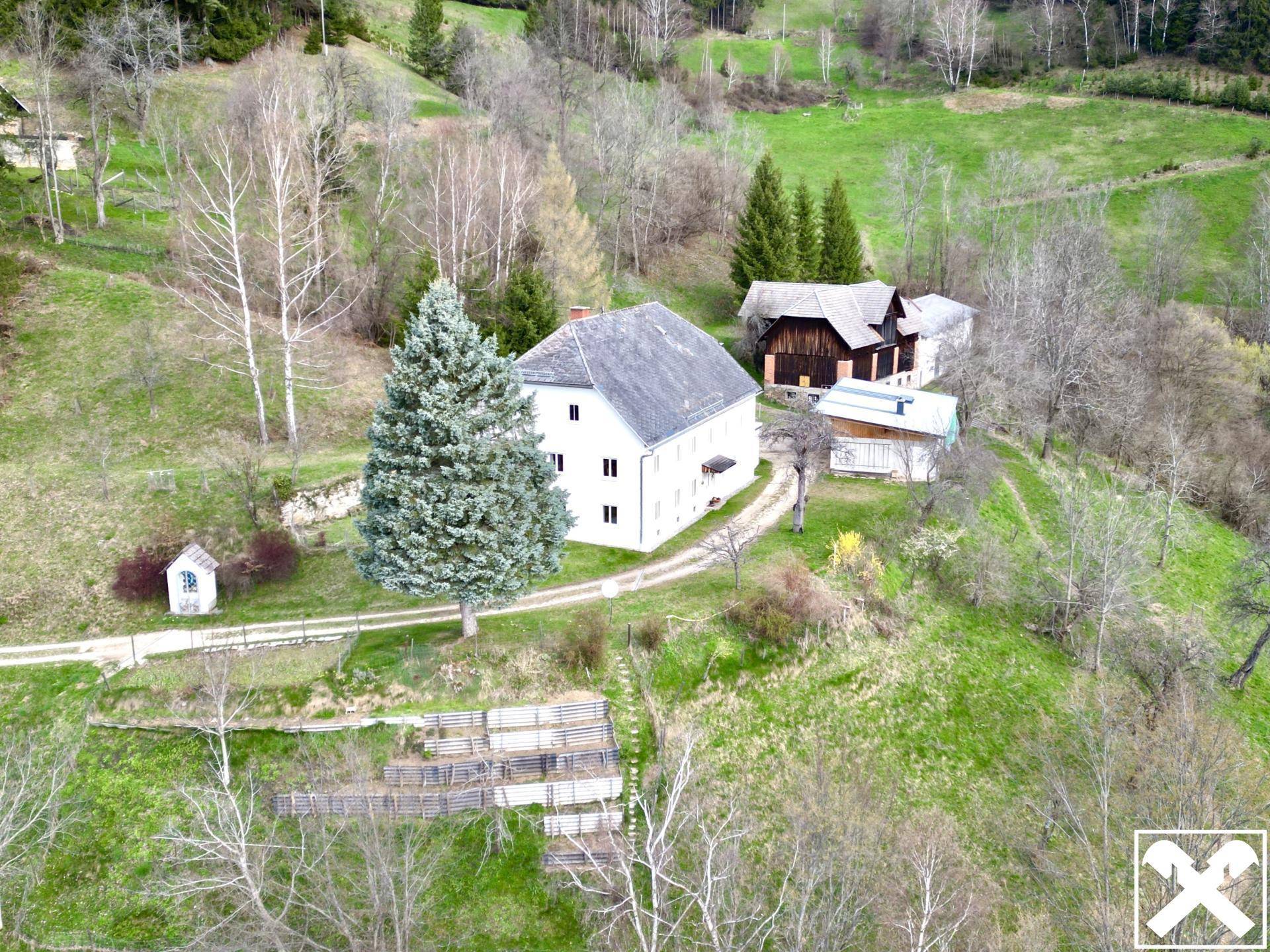 Luftaufnahme des Anwesens mit Haupthaus, Nebengebäuden und weitläufigen Grünflächen.