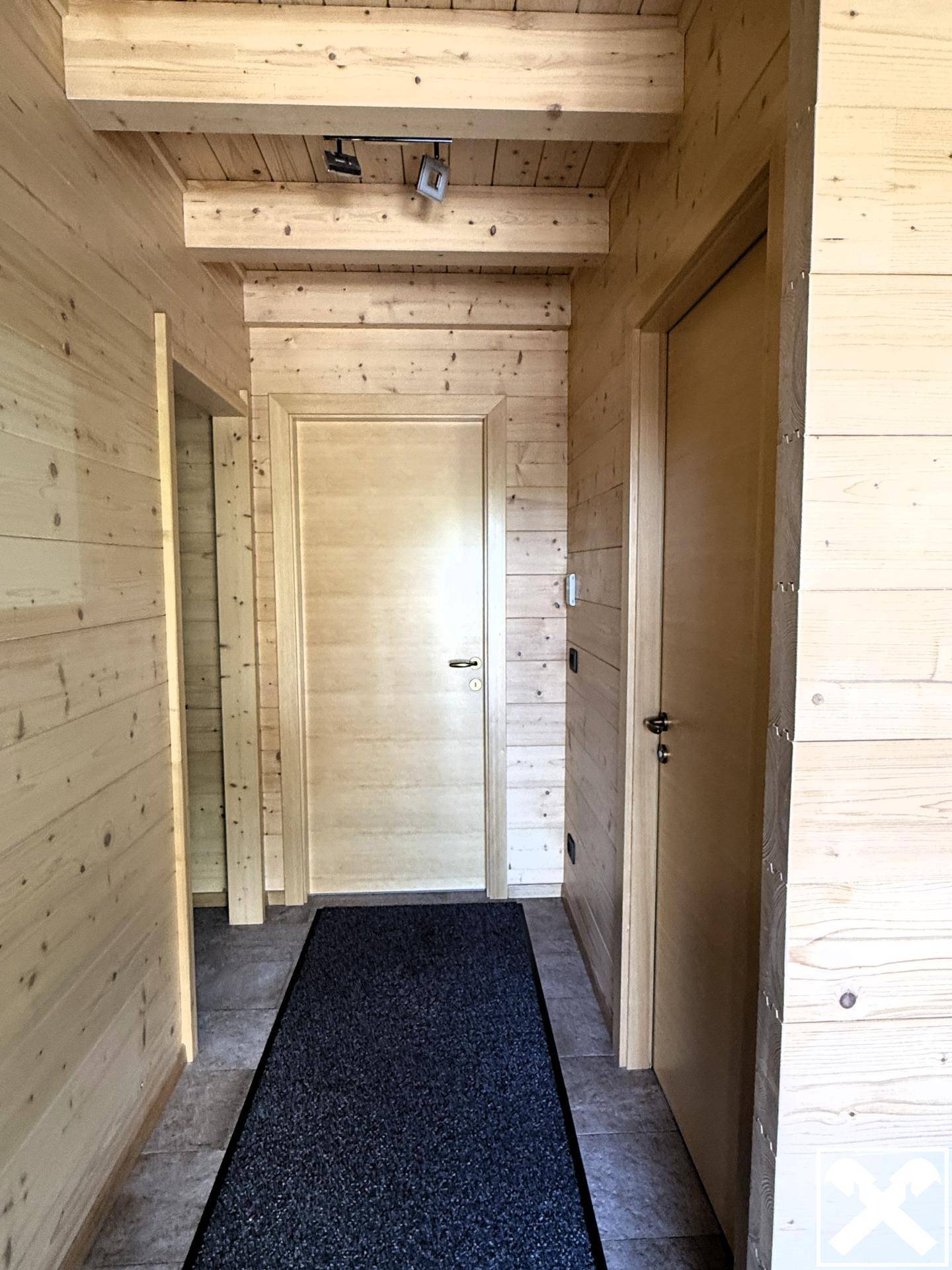 Heller Flur mit Holzvertäfelung an Wänden und Decke sowie Fliesenboden.