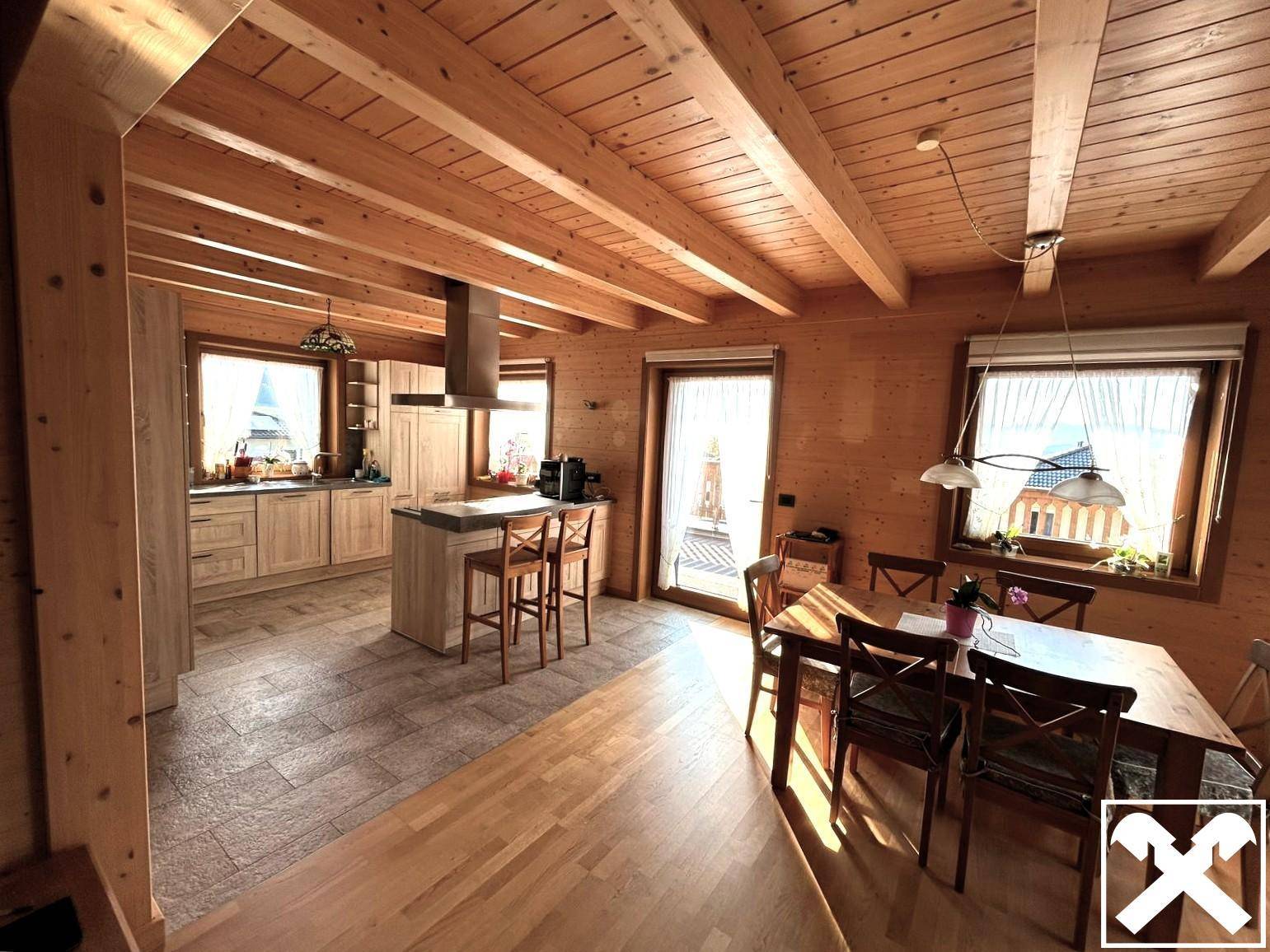Offener Wohn- und Essbereich mit Holzbalkendecke, Holzboden und moderner Küche.