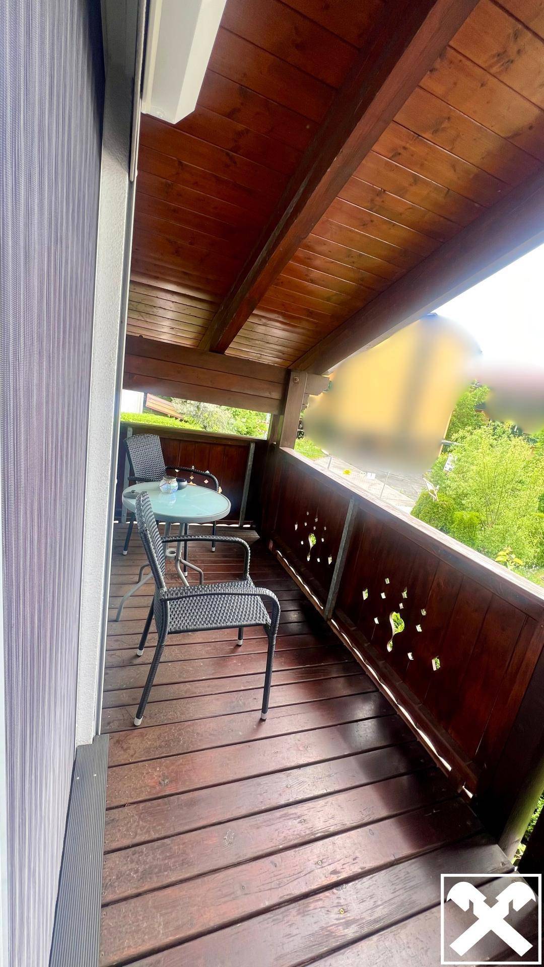 Überdachter Balkon mit Holzboden und Sitzgelegenheiten, ideal für entspannte Stunden im Freien.