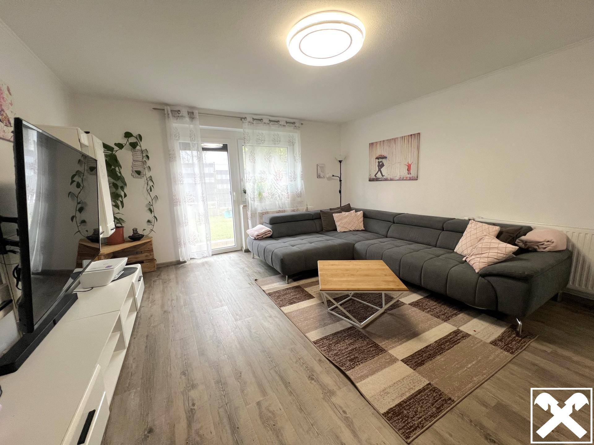 Gemütliches Wohnzimmer mit großem Ecksofa, Fernseher und Zugang zum Garten.