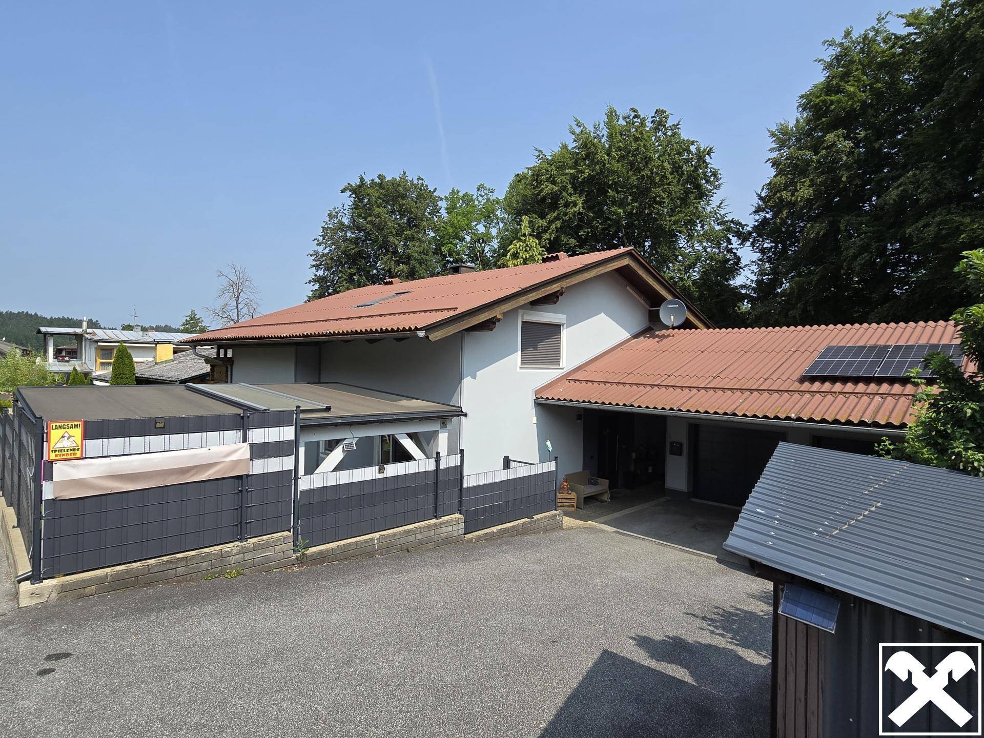 Ansicht des Hauses von oben mit rotem Ziegeldach, Solarpaneelen und Carport.