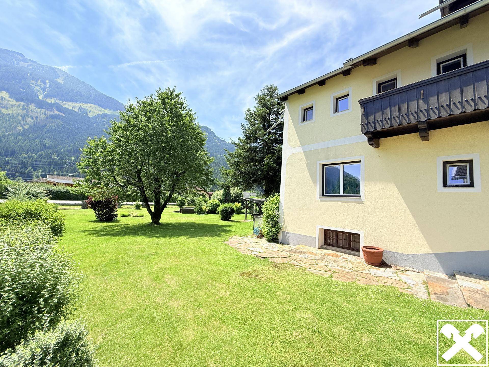 Gepflegter Gartenbereich neben dem Haus mit kleiner Terrasse und malerischem Bergblick.