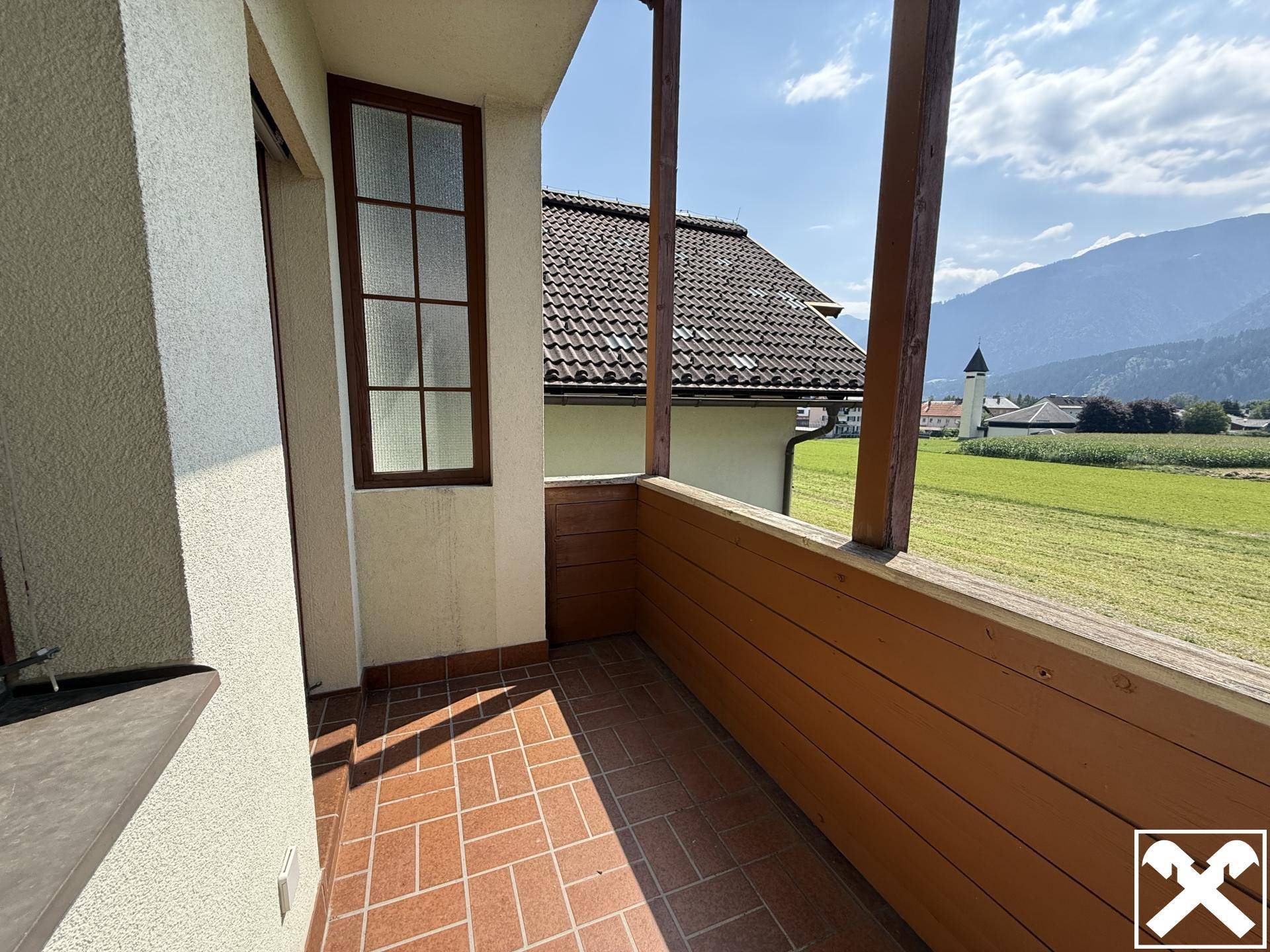 Kleiner Balkon mit Terrakotta-Fliesen und Holzgeländer, bietet einen weiten Blick ins Grüne.
