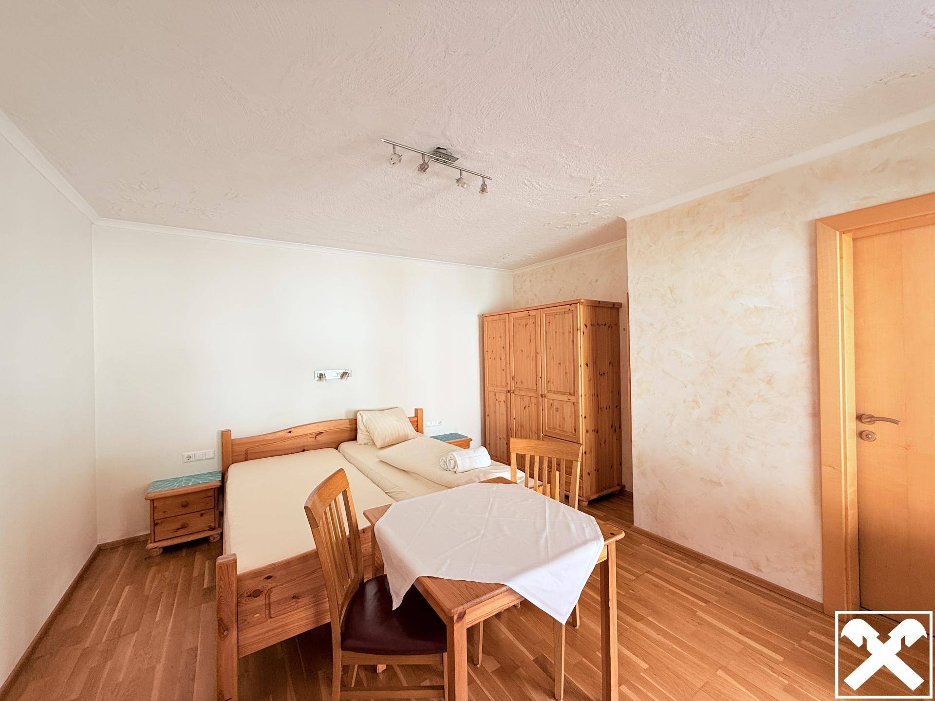 Gemütliches Schlafzimmer mit zwei Einzelbetten, Holzboden und einem Kleiderschrank aus hellem Holz.