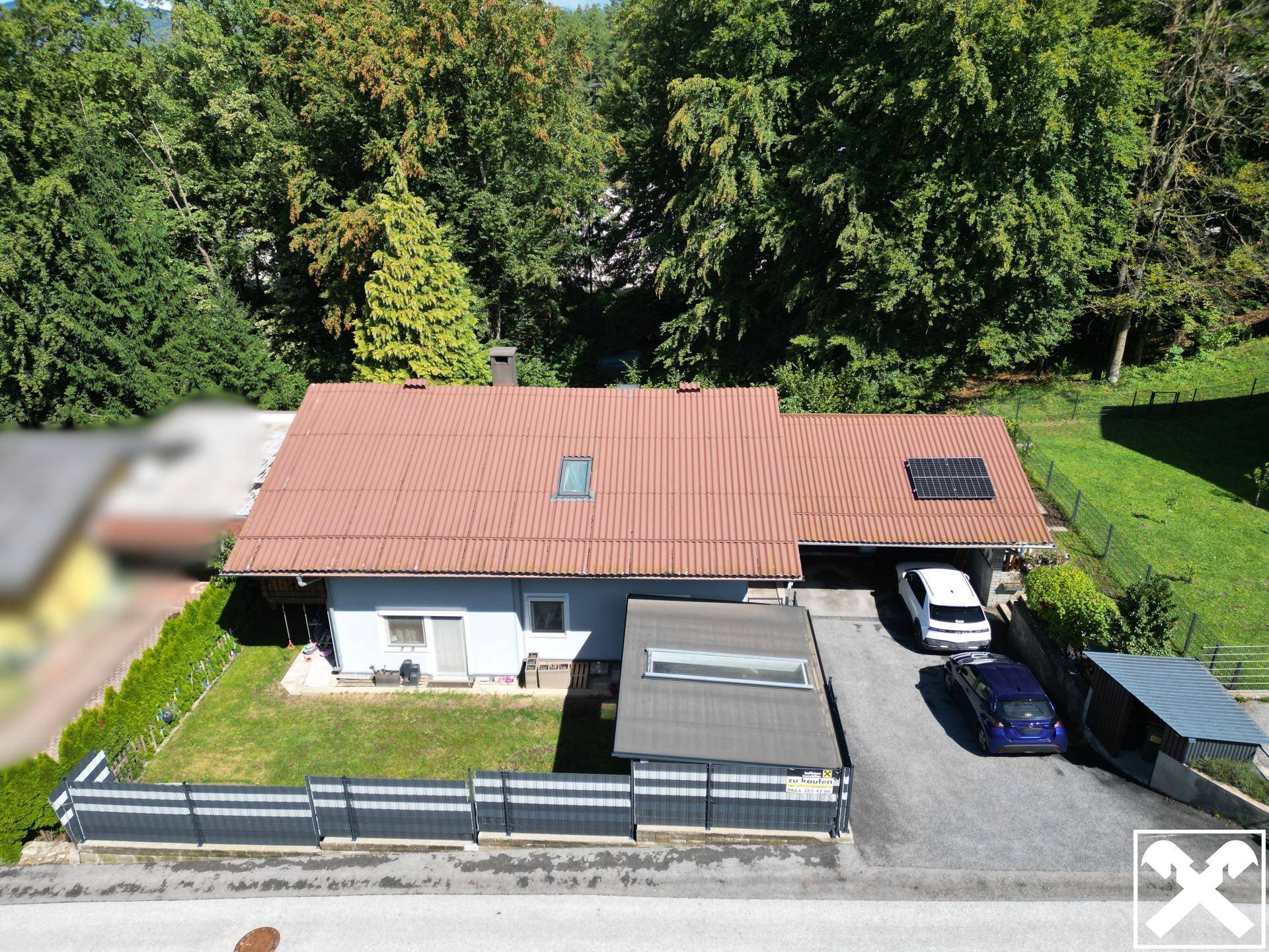 Vogelperspektive des Hauses mit Vorgarten, Zaun und gepflasterter Einfahrt.