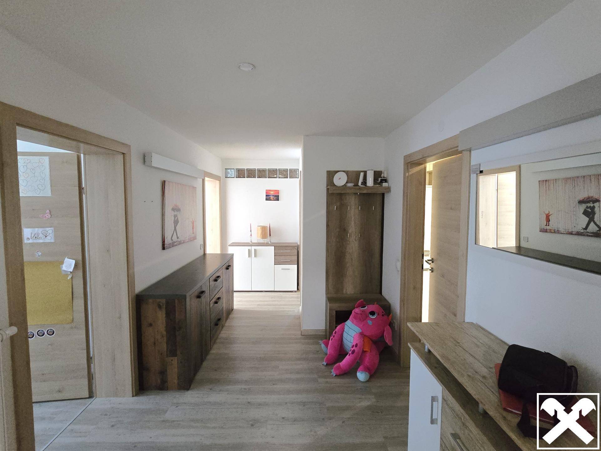 Geräumiger Flur mit Holzmöbeln, Garderobe und einem großen Wandspiegel.