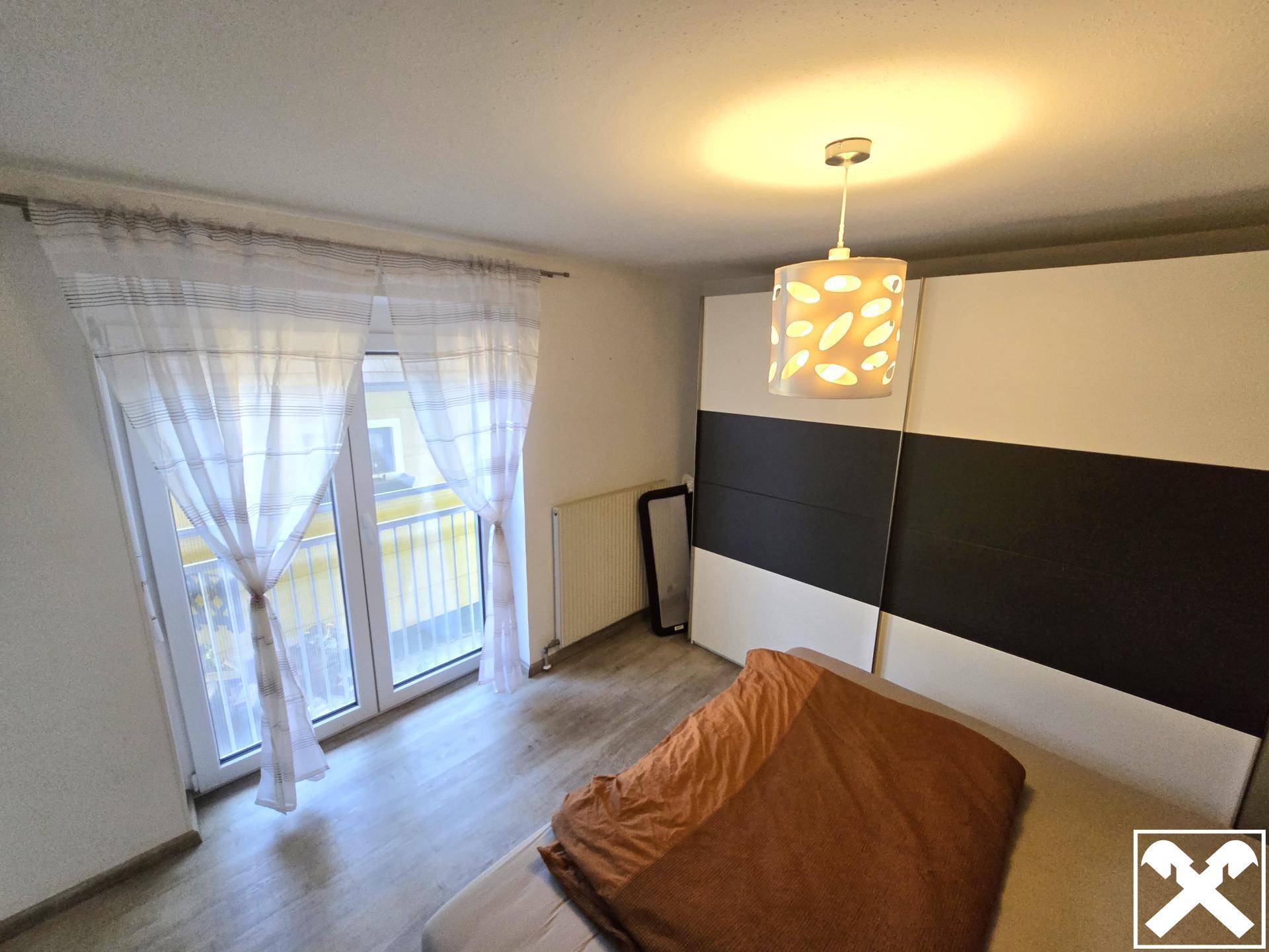 Schlafzimmer mit Doppelbett, großem Kleiderschrank und Zugang zu einem französischen Balkon.