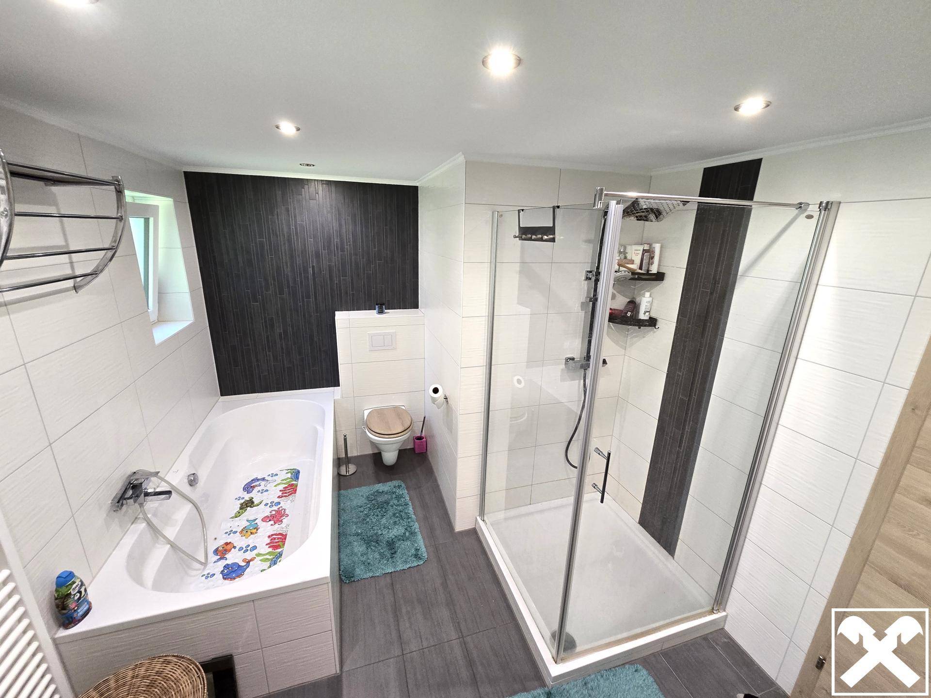 Modernes Badezimmer mit Badewanne, Duschkabine und wandhängendem WC.