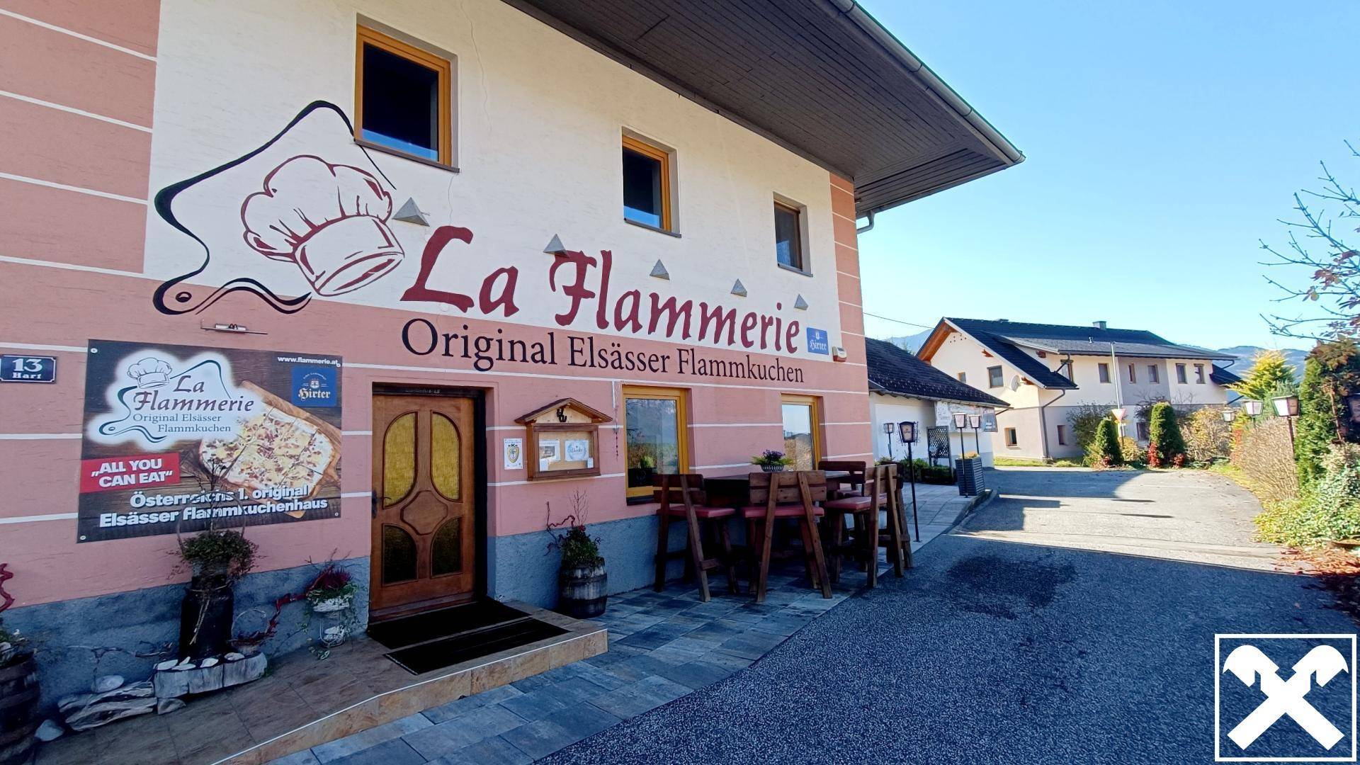 Haupteingang des Restaurants mit Außensitzplätzen und der charakteristischen rosa Fassade, die zum Verweilen einlädt.