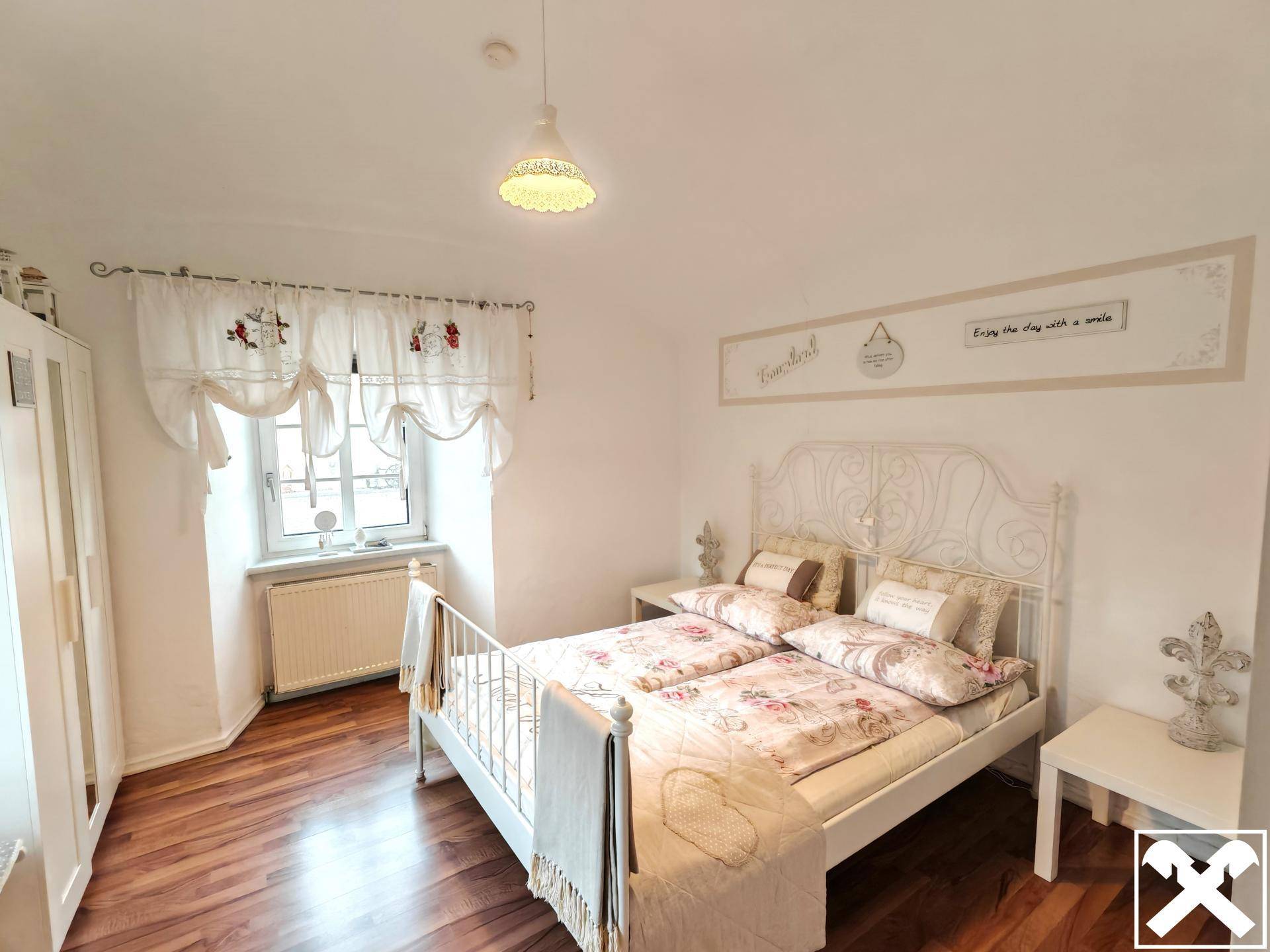 Gemütliches Schlafzimmer mit Holzboden, Fenster und traditioneller Dekoration.