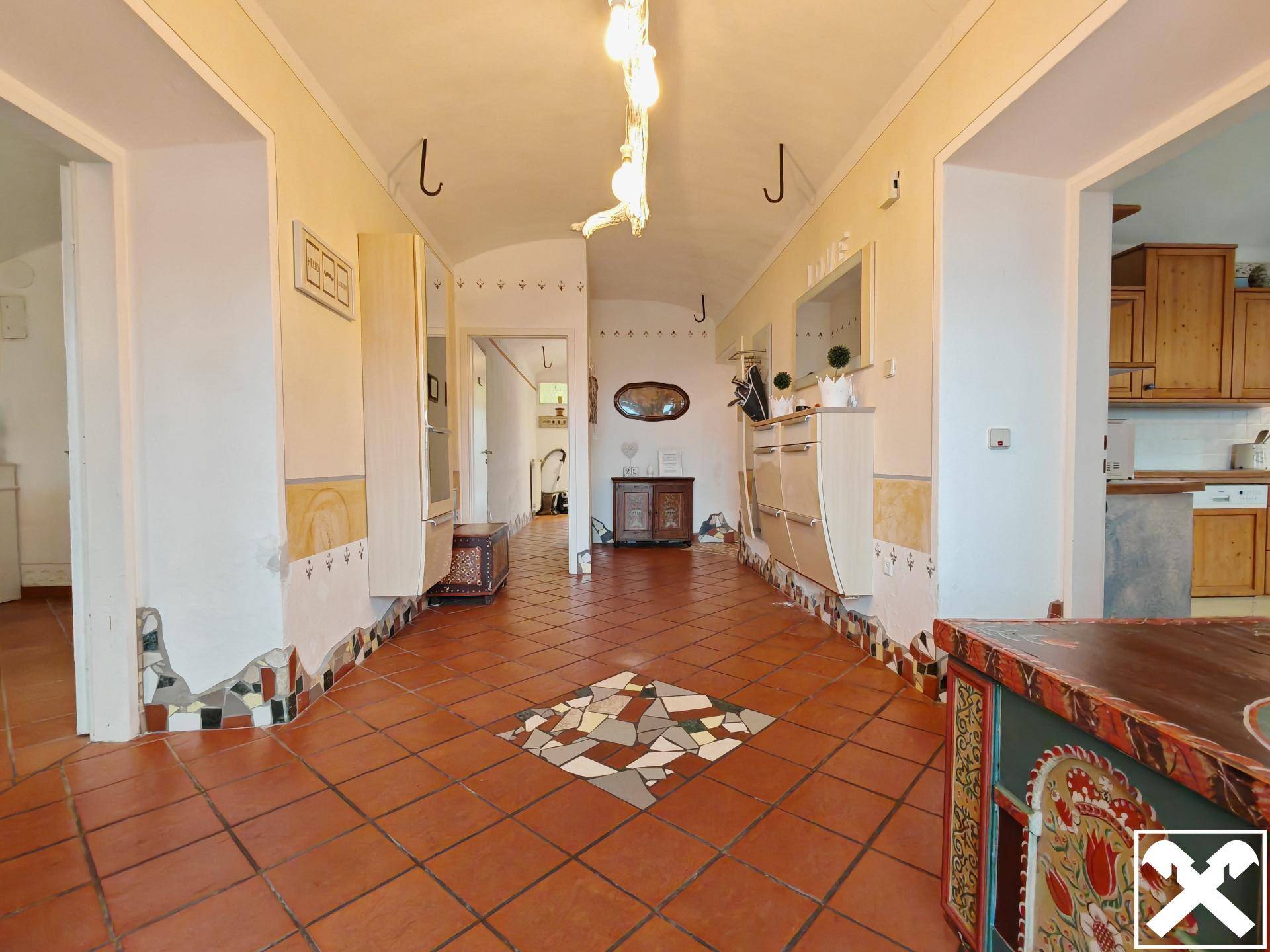 Geräumiger Flur mit Terrakotta-Fliesenboden und traditionellen Dekorationen, der zu weiteren Räumen führt.