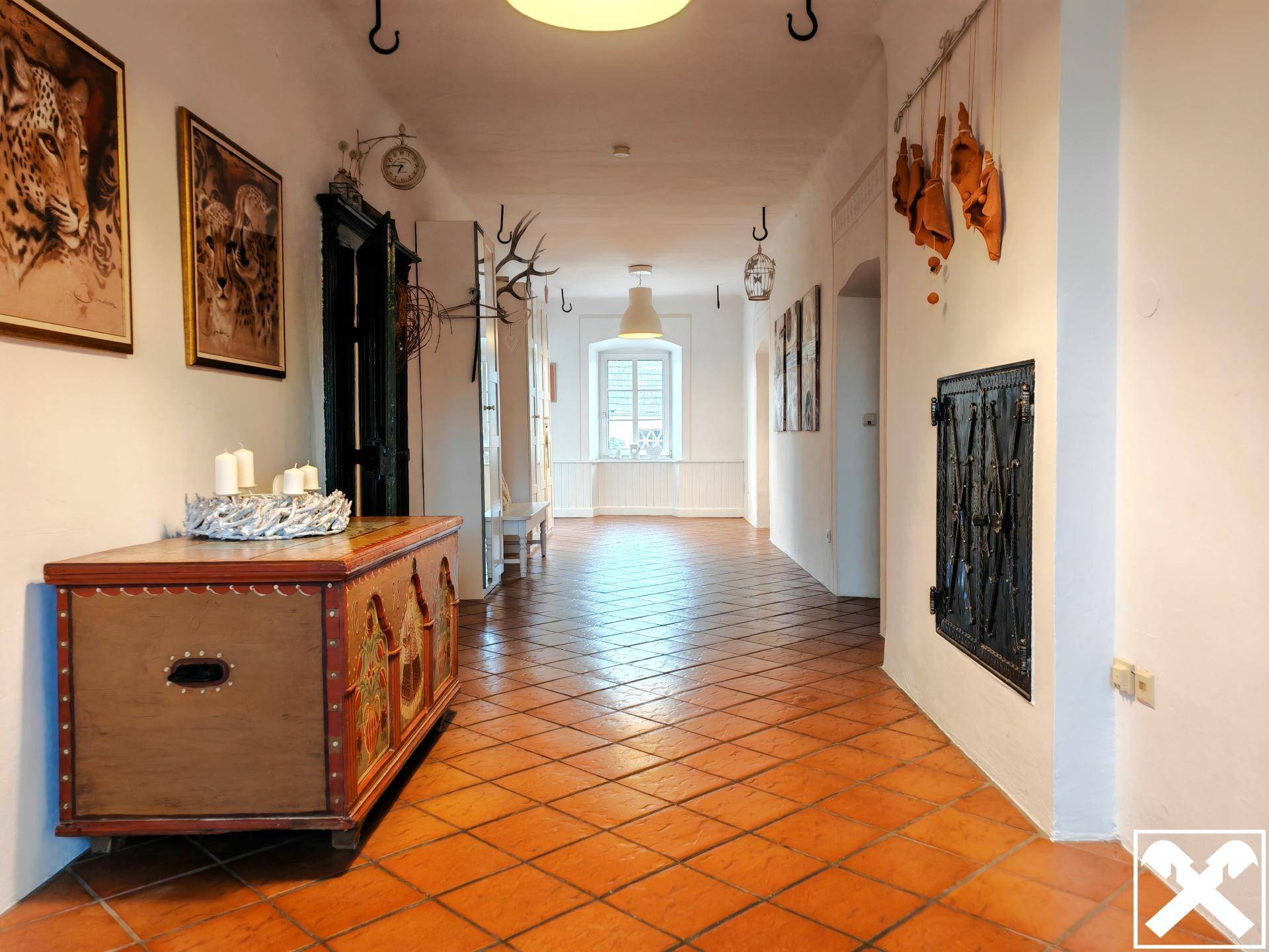 Langer Flur mit Terrakotta-Fliesenboden, gewölbter Decke und traditionellen Dekorationen.