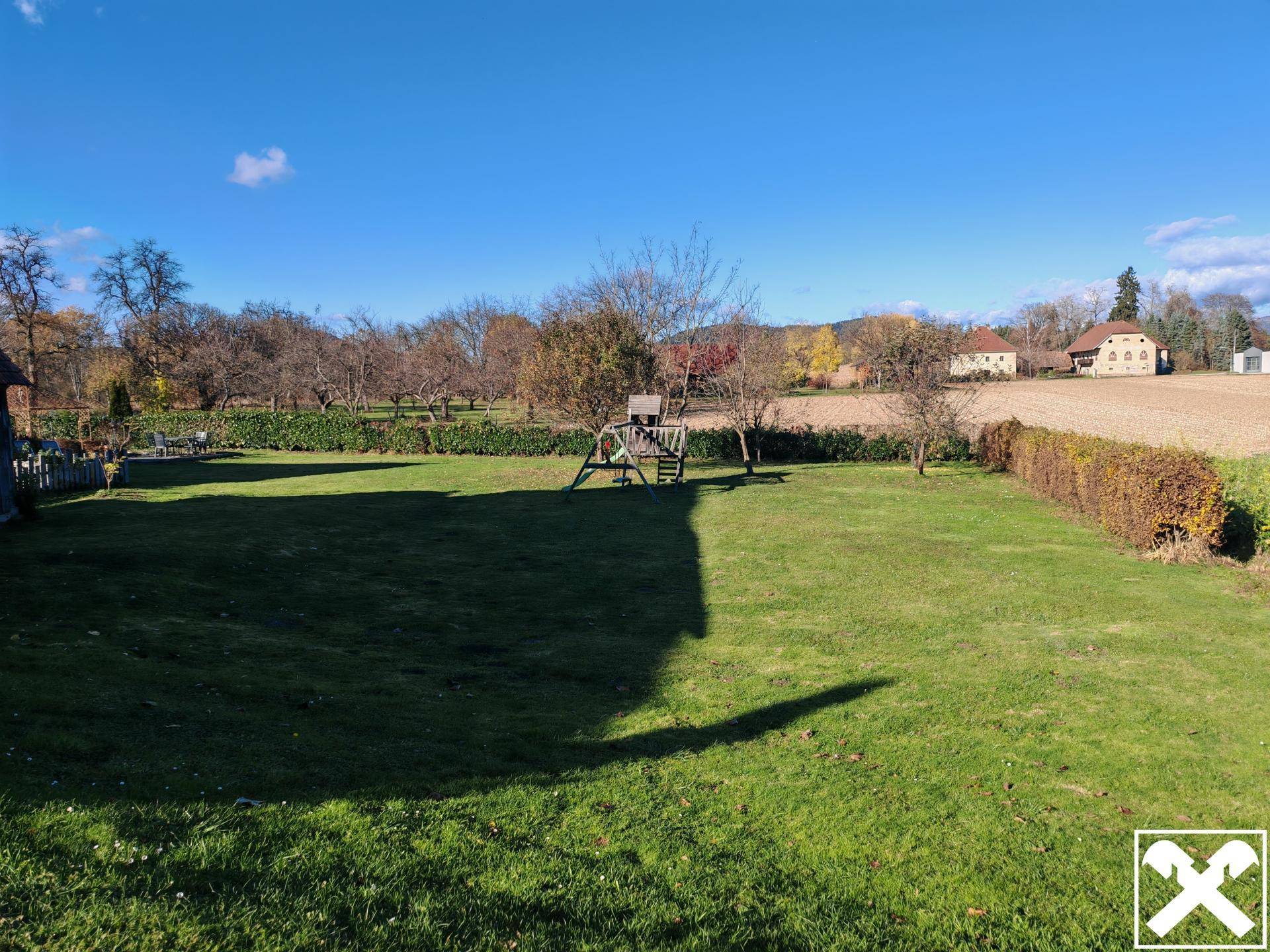 Weitläufige Rasenfläche mit Kinderspielplatz und Blick auf die ländliche Umgebung.