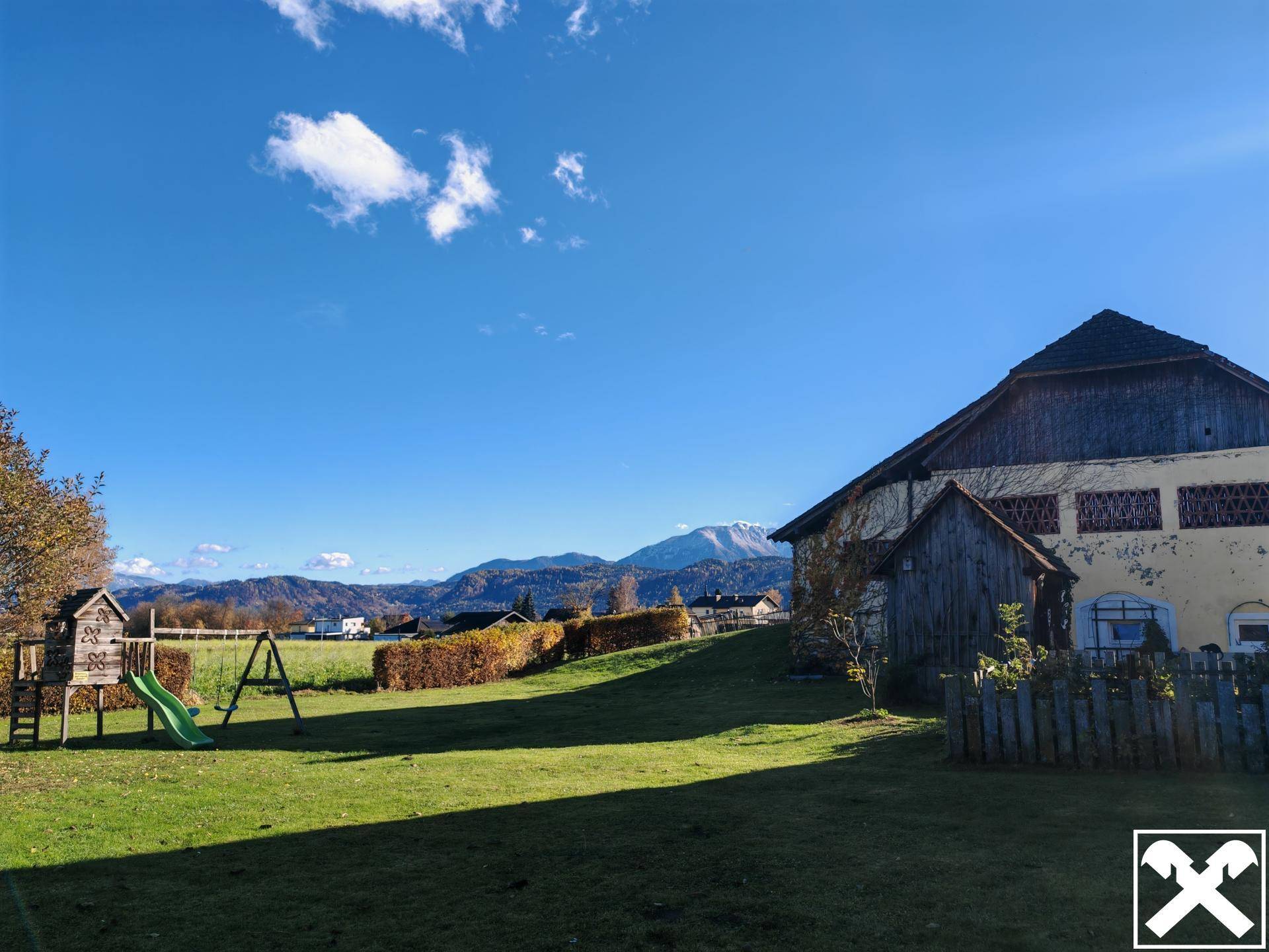 Großer Garten mit Spielplatz, weitem Rasen und beeindruckendem Bergblick.