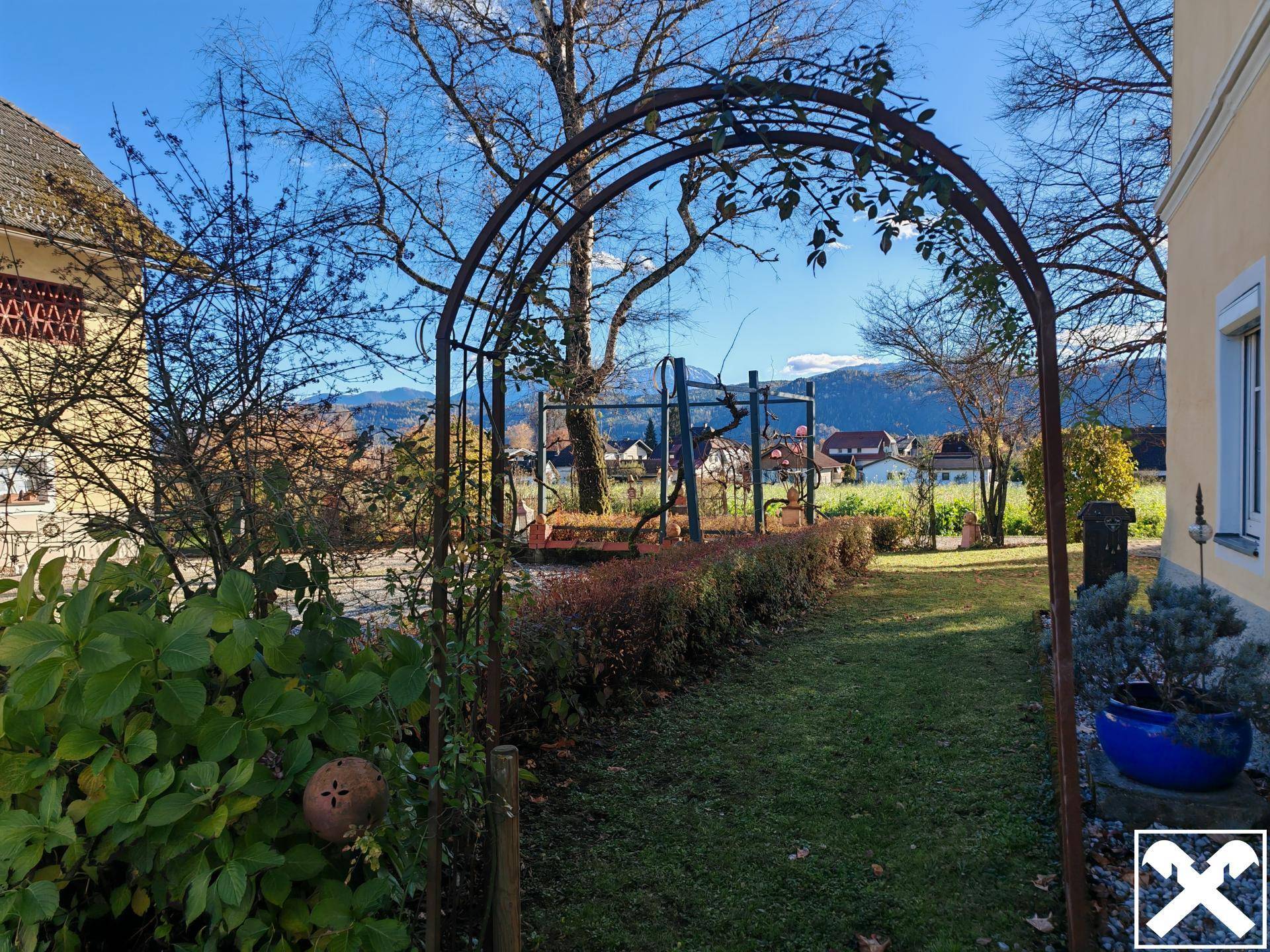 Gepflegter Gartenbereich mit einem dekorativen Torbogen und Blick auf die umliegende Landschaft.