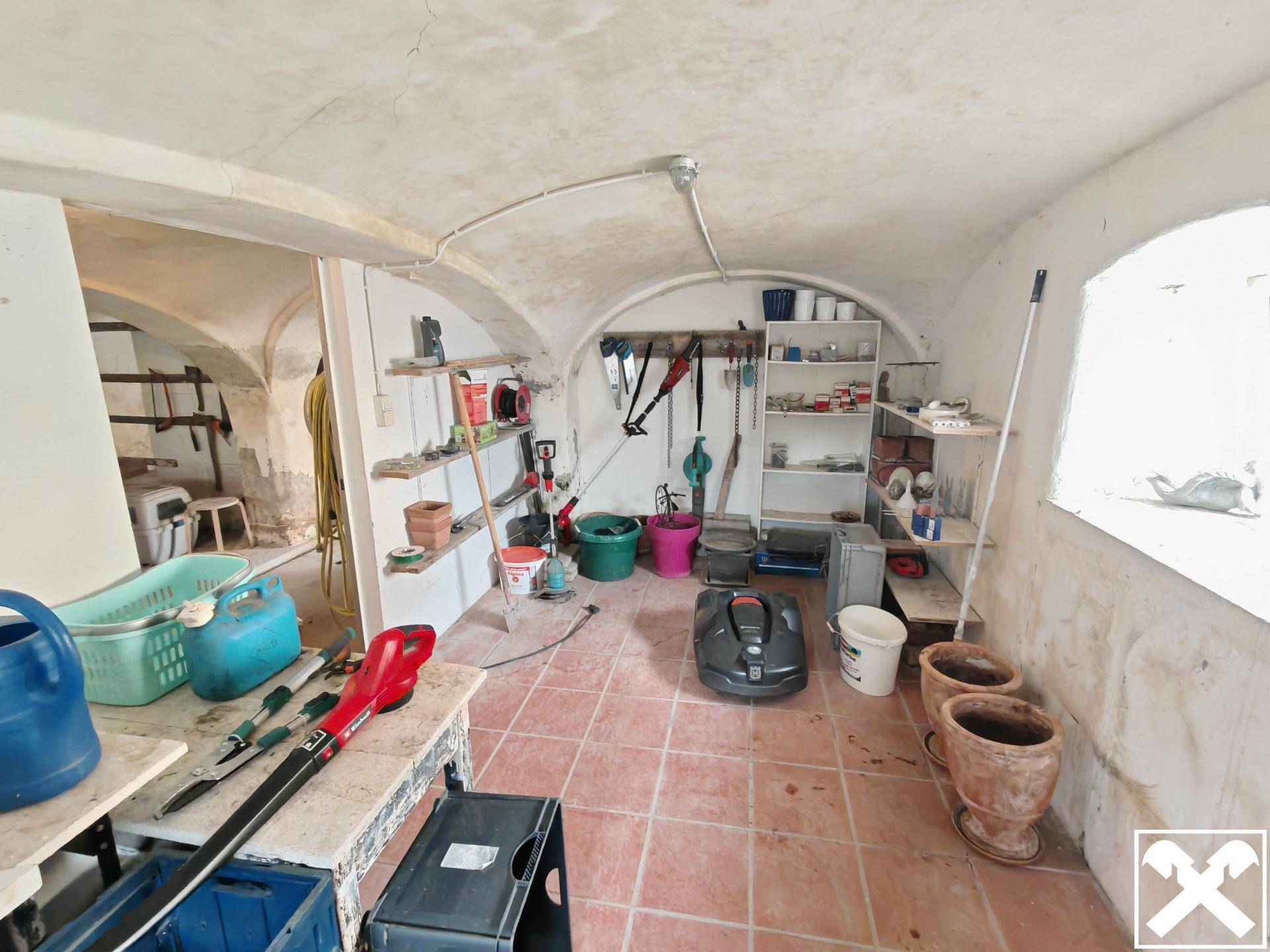 Praktischer Abstellraum im Gewölbekeller mit Regalen und Werkzeugen.