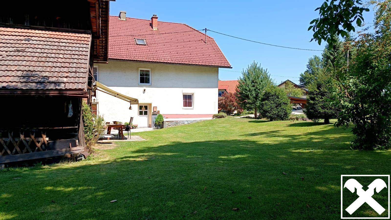 Weitläufiger Rasenbereich neben dem Wohnhaus und dem rustikalen Nebengebäude.