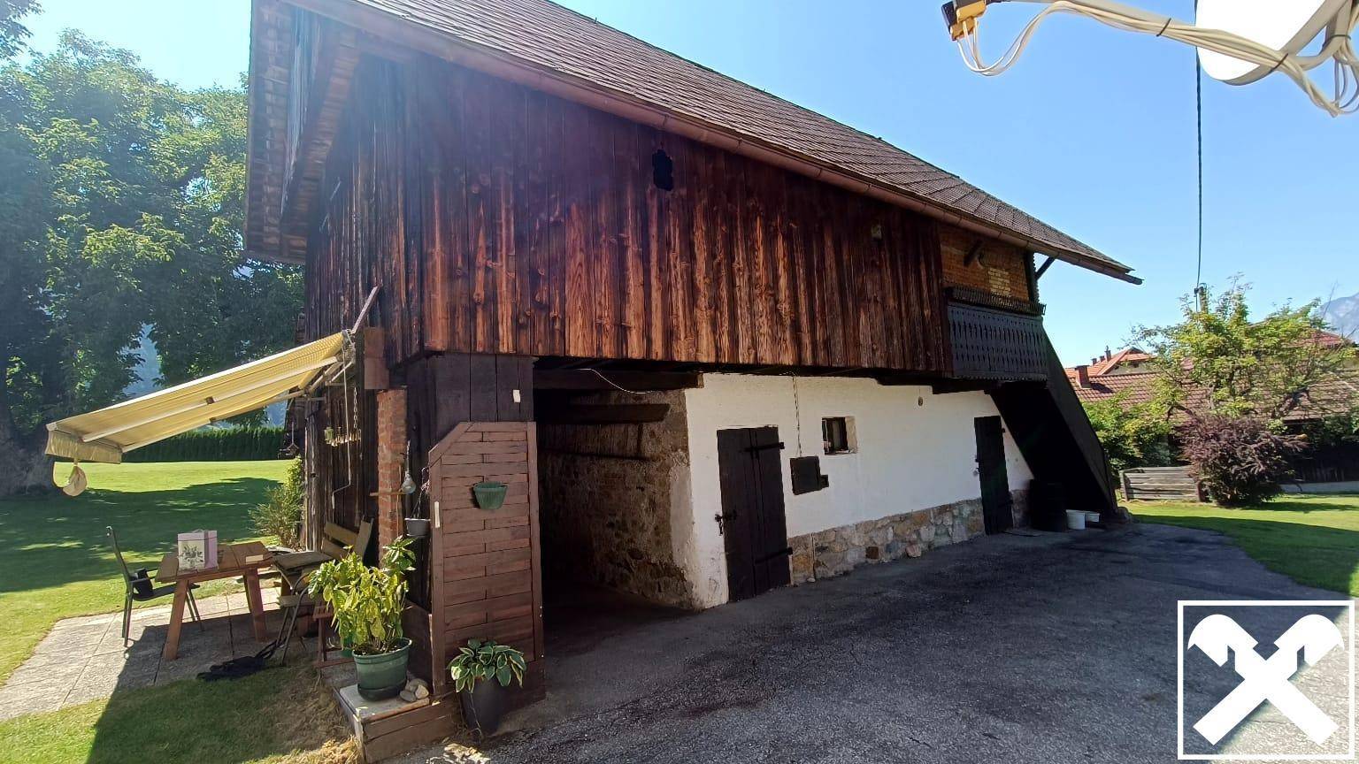 Rustikales Nebengebäude mit Holzelementen und einem kleinen, gemütlichen Sitzbereich im Freien.