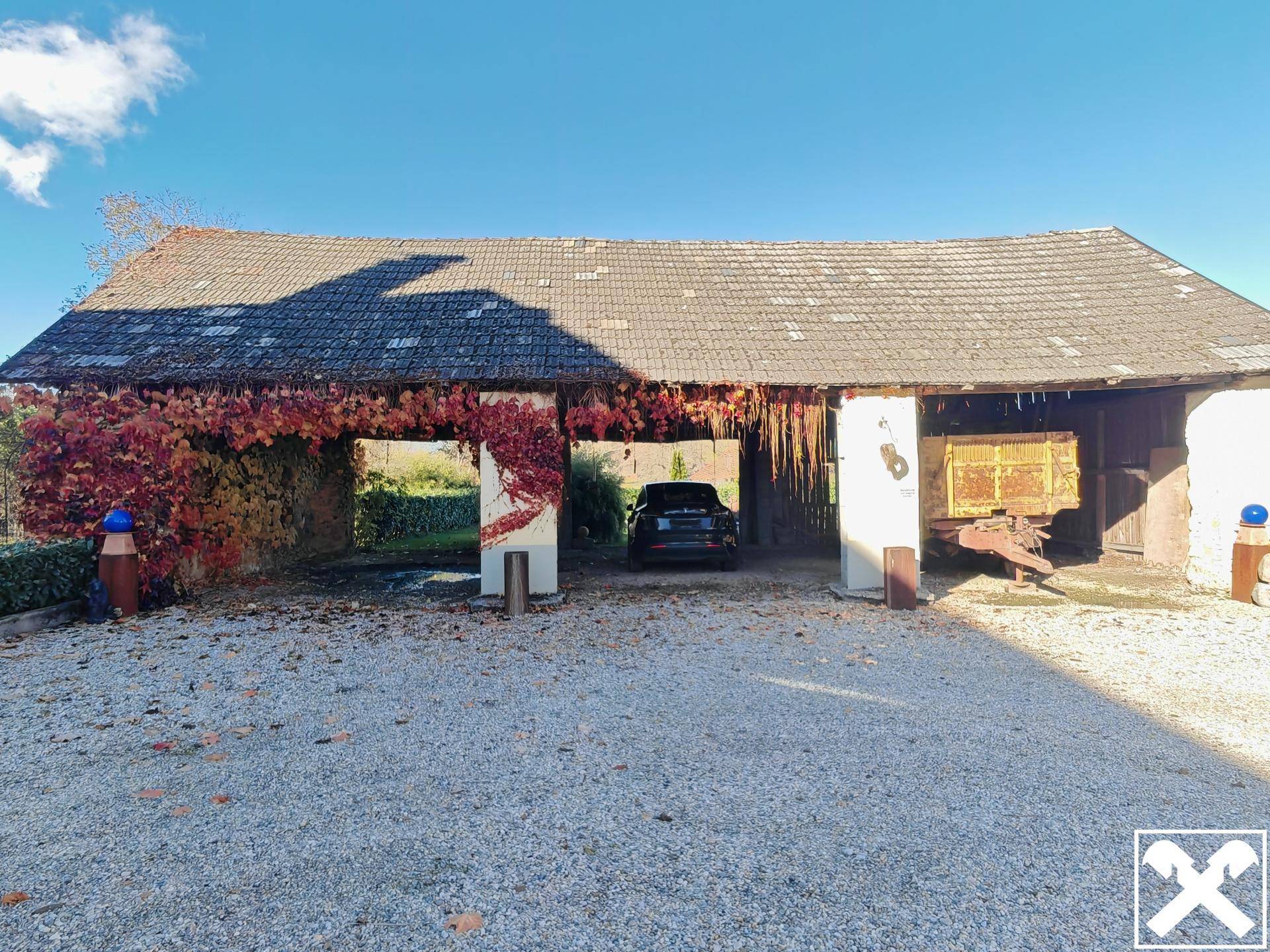 Überdachter Bereich mit Parkmöglichkeit und rustikalen Holzelementen.