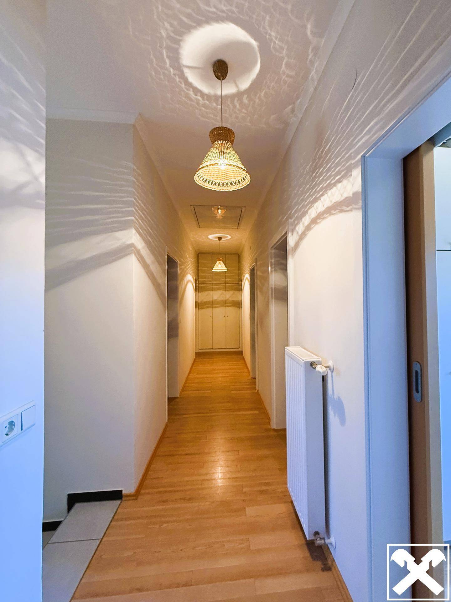 Heller Flur mit Holzfußboden und mehreren Türen, der zu den Zimmern führt.