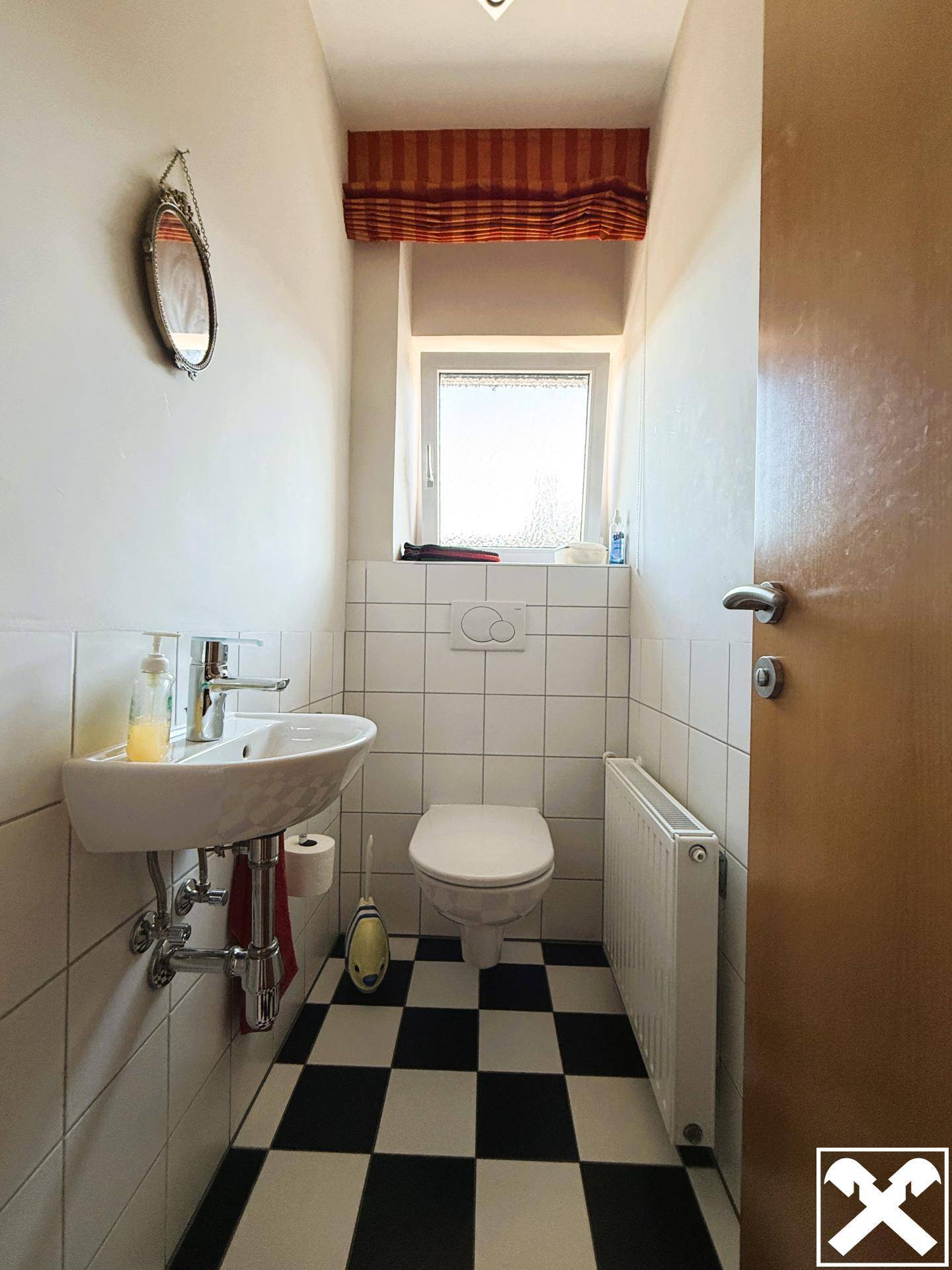 Kleines Gäste-WC mit Schachbrettmuster-Fliesen, Fenster und Wand-WC.