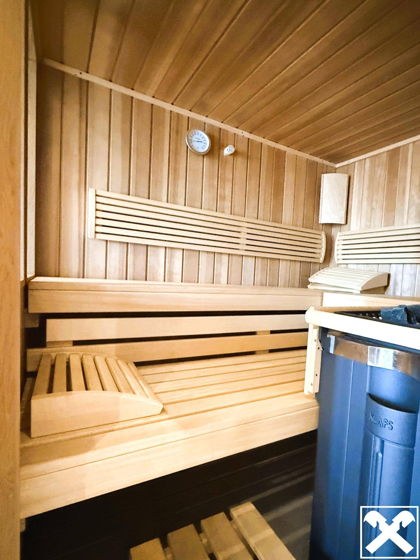 Holzvertäfelte Sauna mit Bänken und Saunaofen, ideal zur Entspannung.