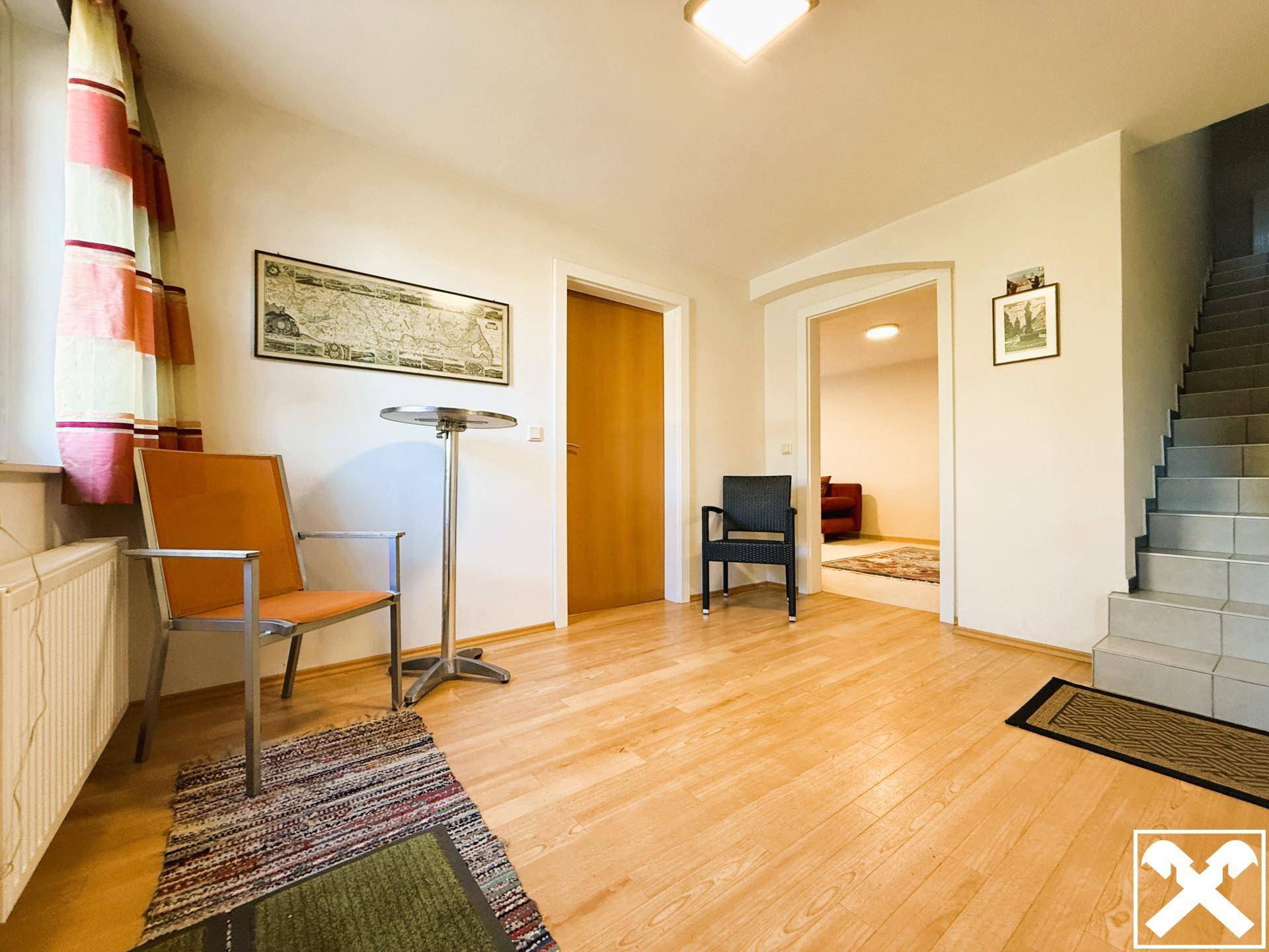 Heller Eingangsbereich mit Holzfußboden, Sitzgelegenheiten und Zugang zu einer Treppe.