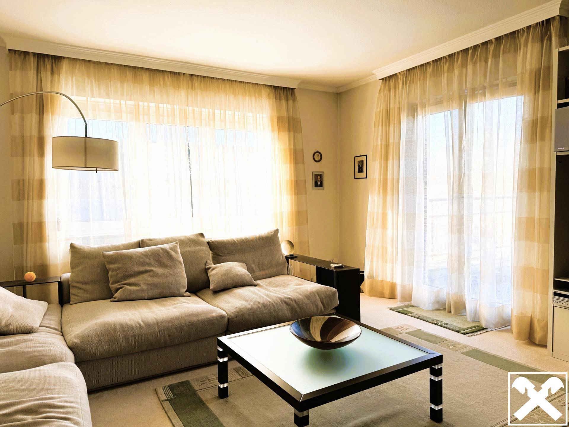 Helles Wohnzimmer mit großem Sofa, Couchtisch und Zugang zu einem Balkon.