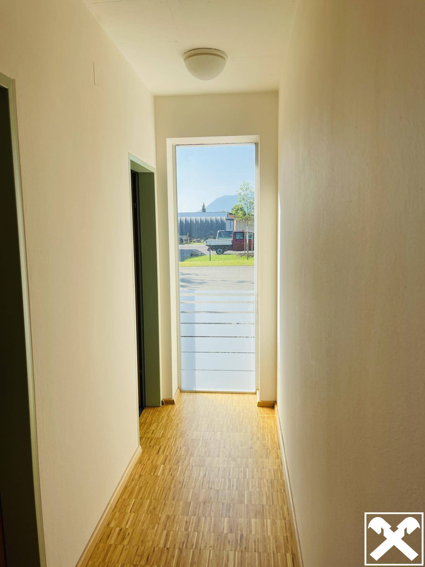 Heller Flur mit Holzboden und Fenster, das einen Blick auf die Umgebung ermöglicht.