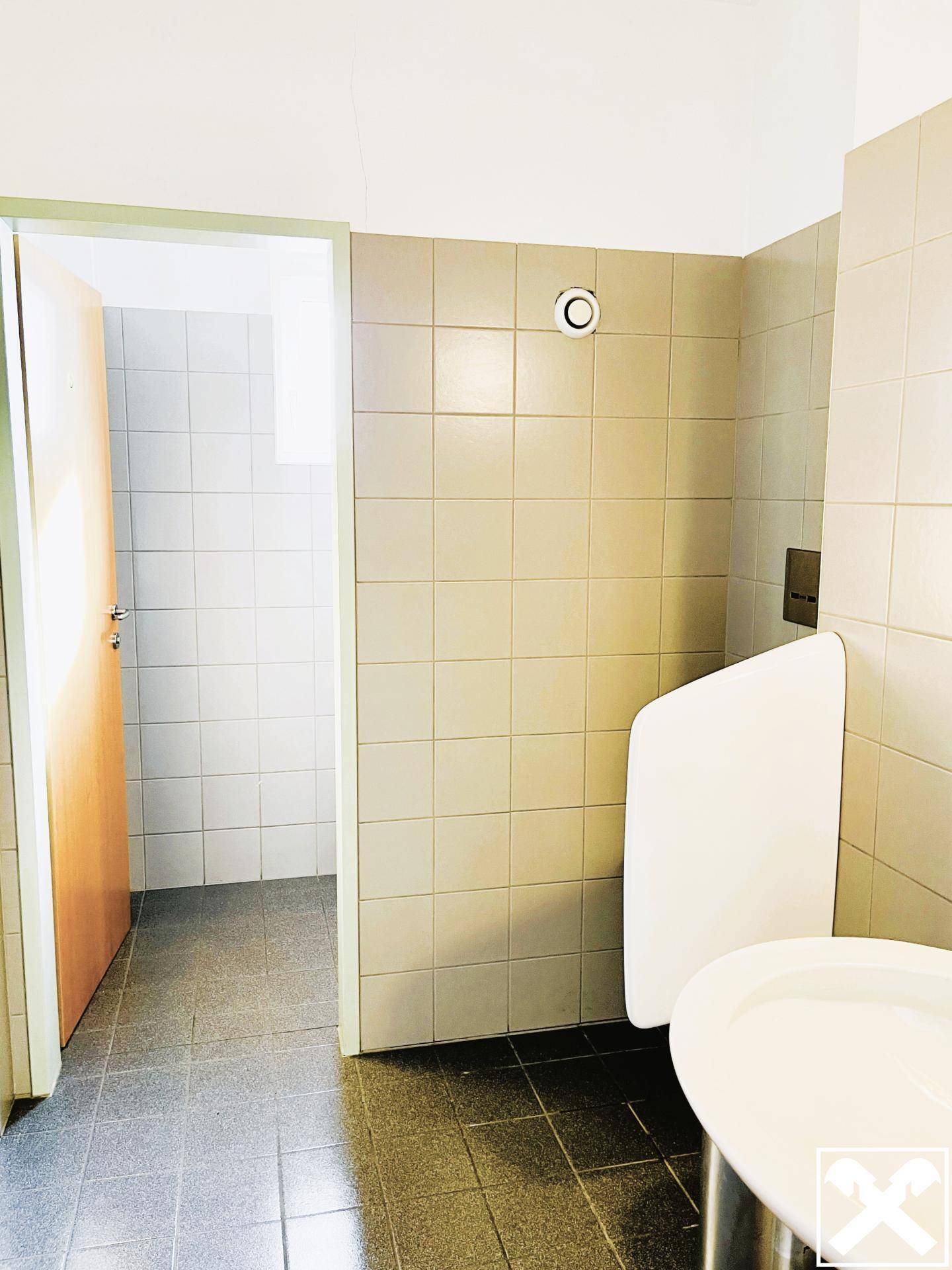Badezimmer mit Urinal und gefliesten Wänden, funktional und sauber gehalten.