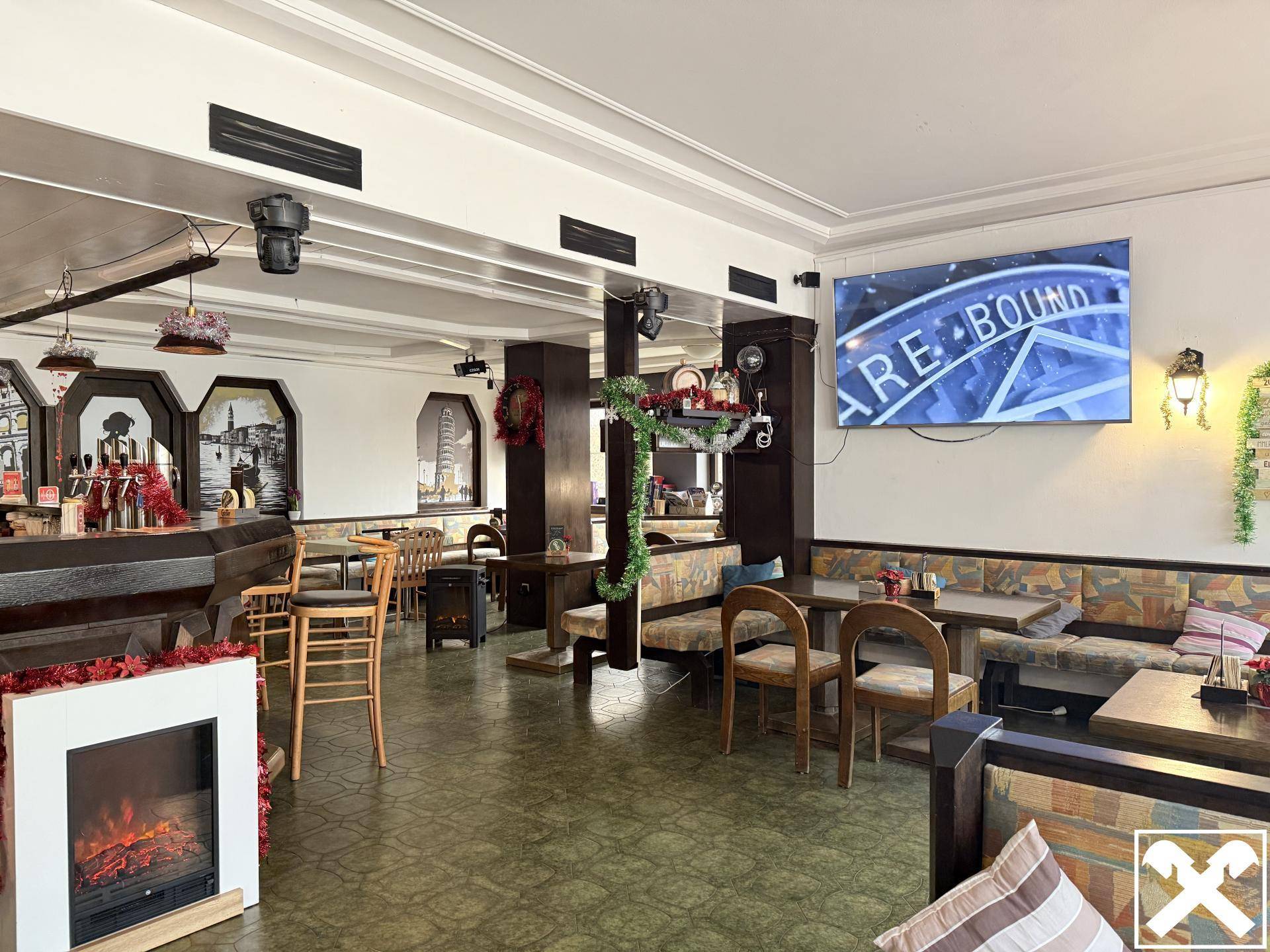 Gastraum eines Pubs mit Tischen, Bänken, einer Bar und einem großen Fernseher, festlich dekoriert.