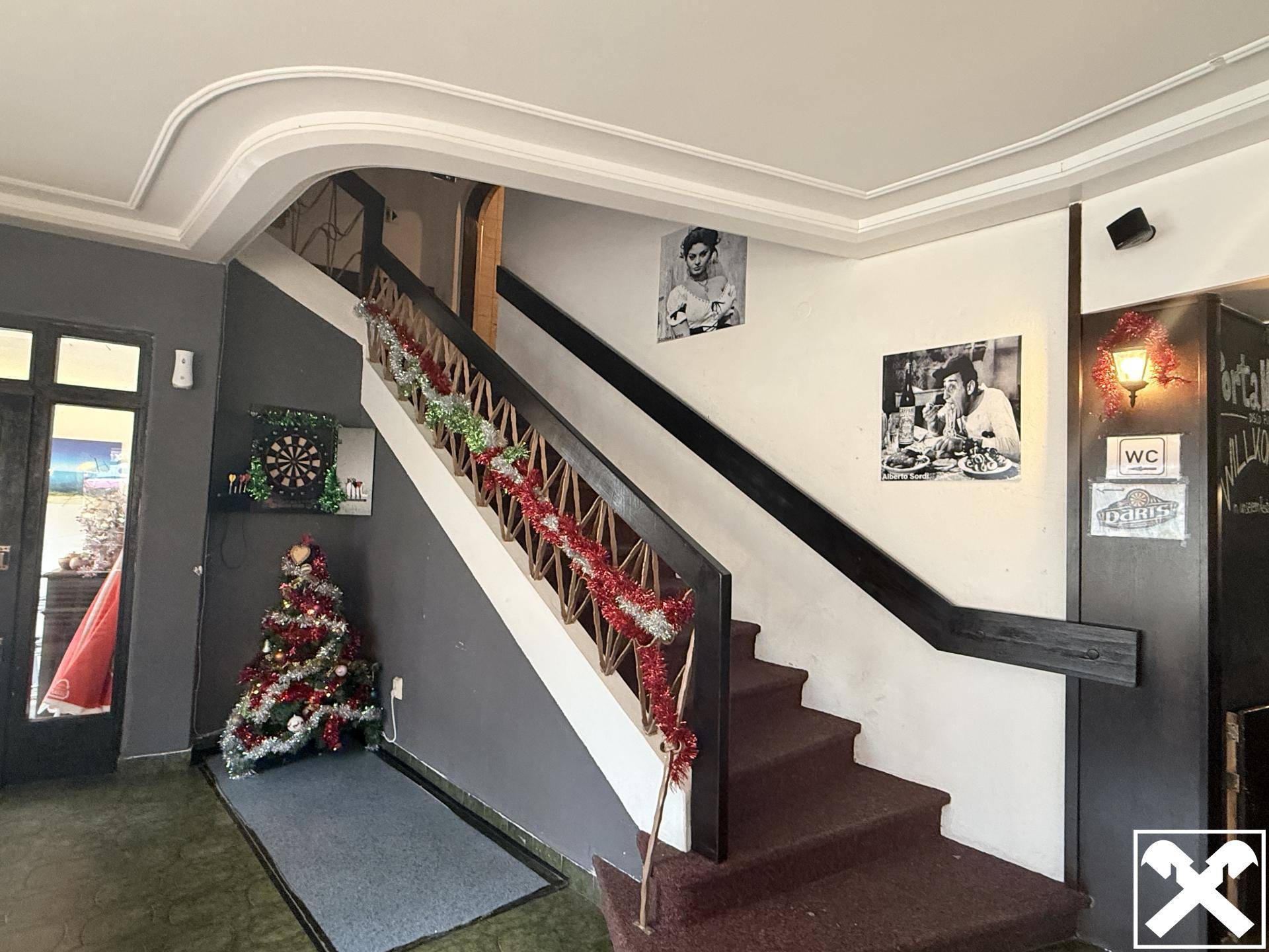 Treppenhaus im Gewerbegebäude mit festlicher Dekoration und Bildern an der Wand, die nach oben führt.