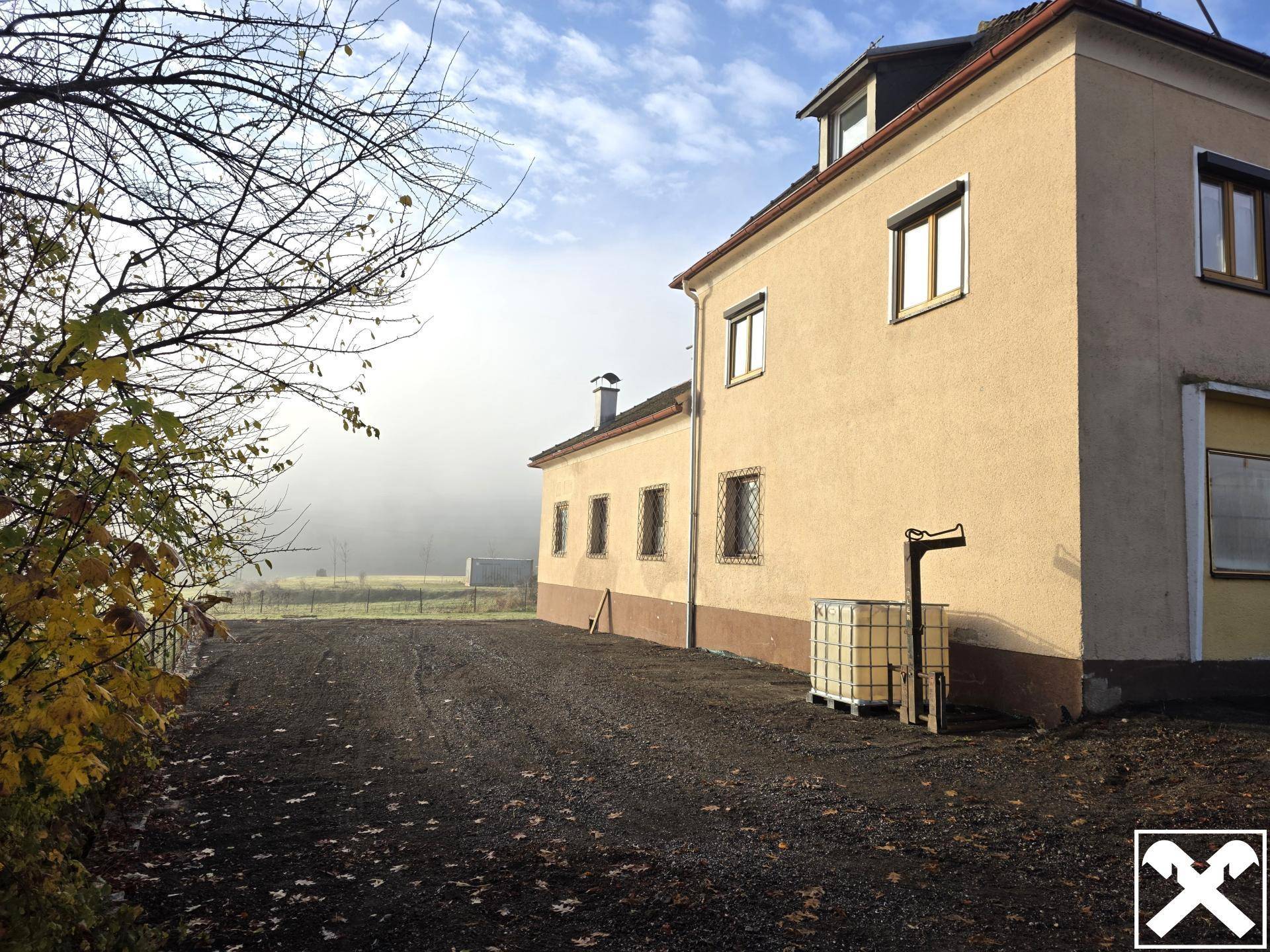 Seitenansicht des Gebäudes mit ländlicher Umgebung und einem nebligen Horizont am Morgen.