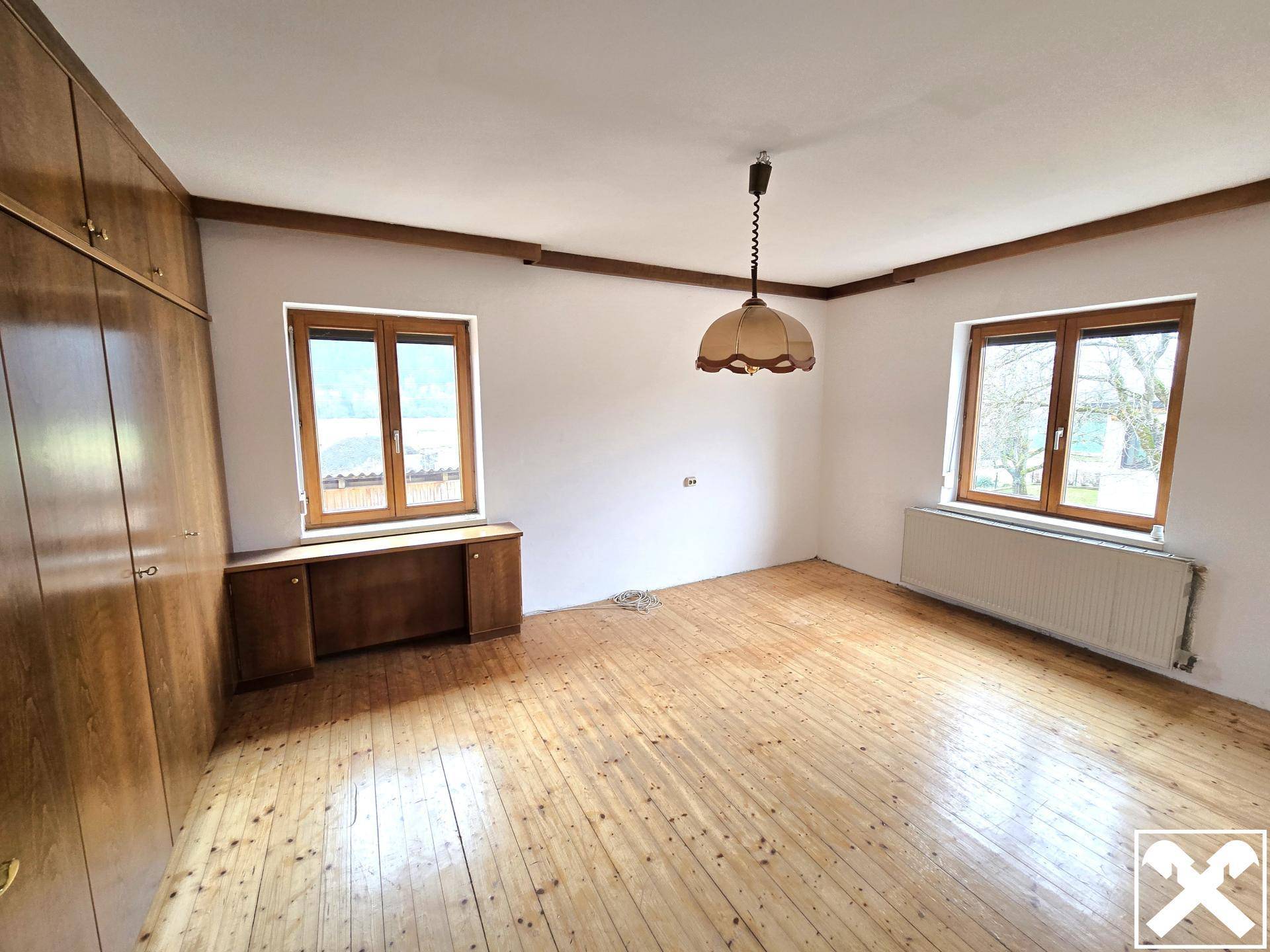 Schlafzimmer mit Holzdielenboden und eingebauten Holzschränken, die Stauraum bieten.