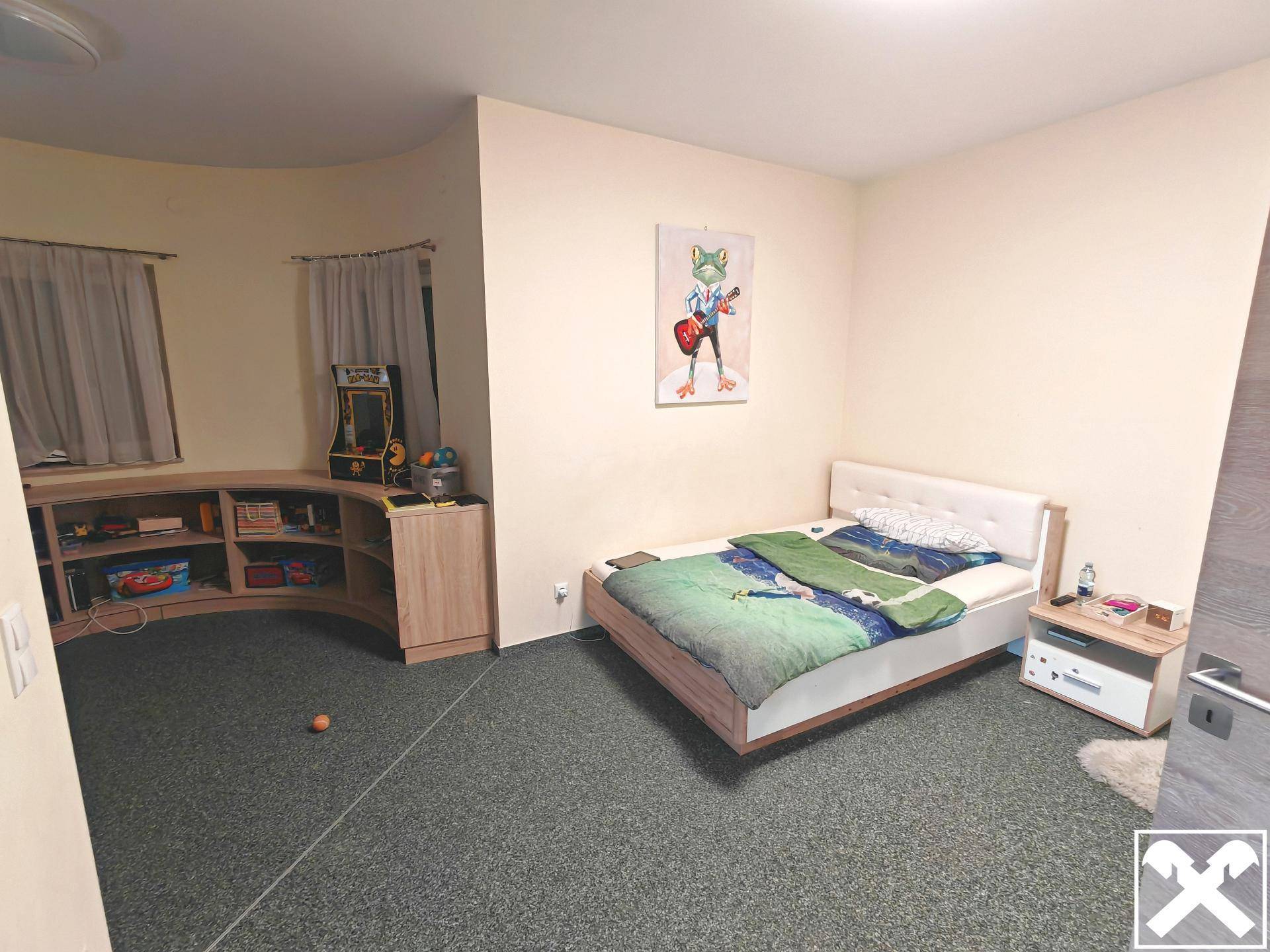 Schlafzimmer mit Bett, Nachttisch und Teppichboden in einem runden Raumteil.