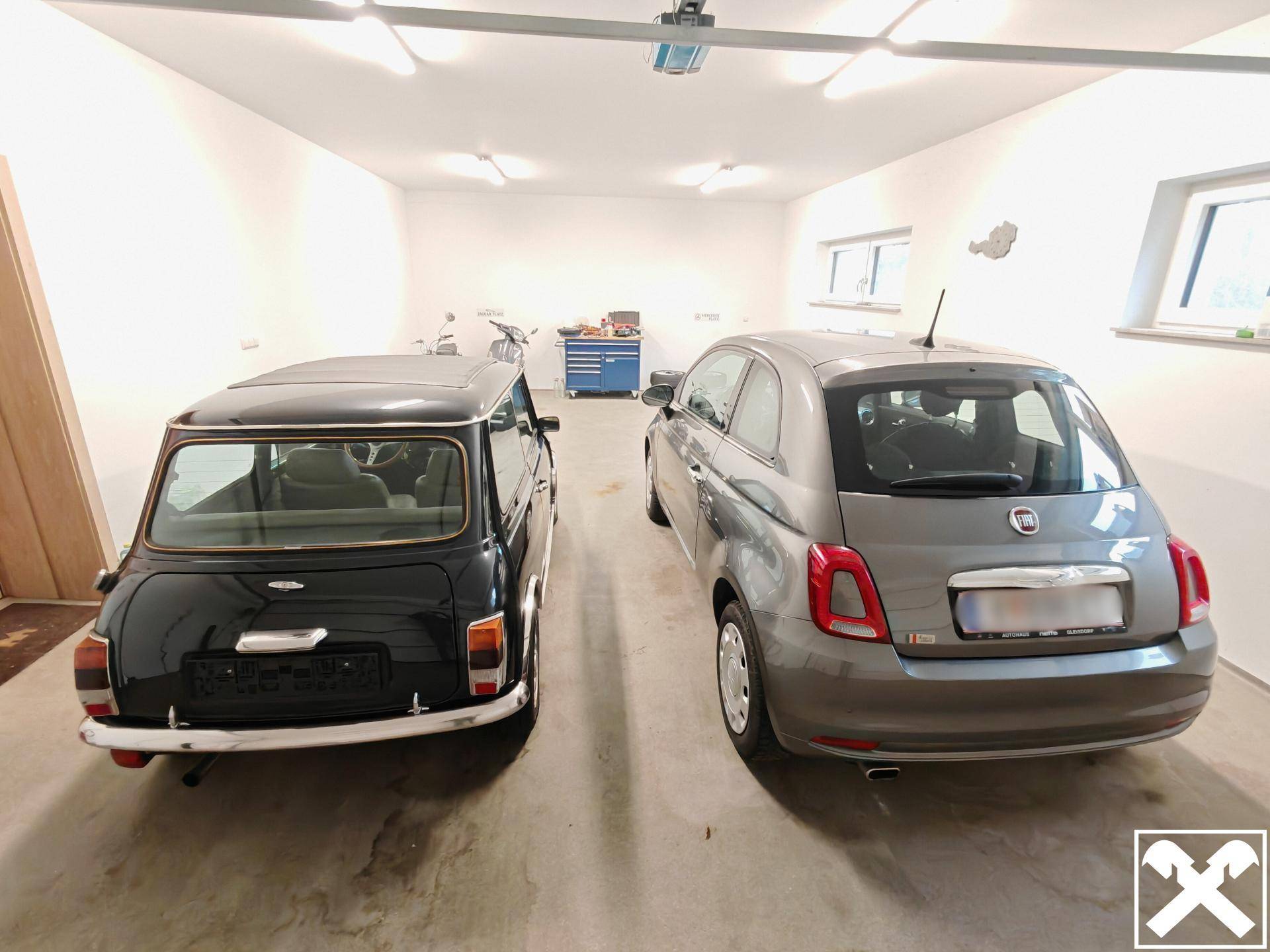 Geräumige Garage mit zwei Autos, Werkzeugschrank und Fenstern.