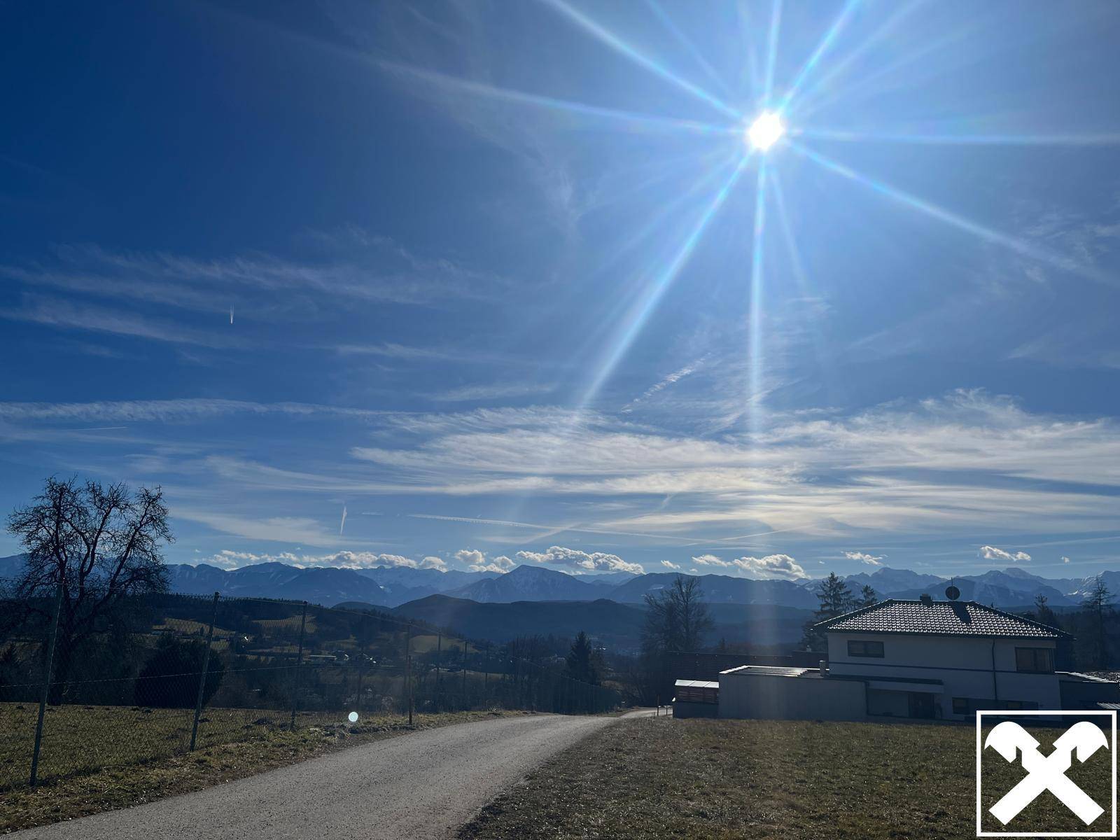 Weitläufiger Blick auf die schneebedeckten Berge und die umliegende Landschaft an einem sonnigen Tag.