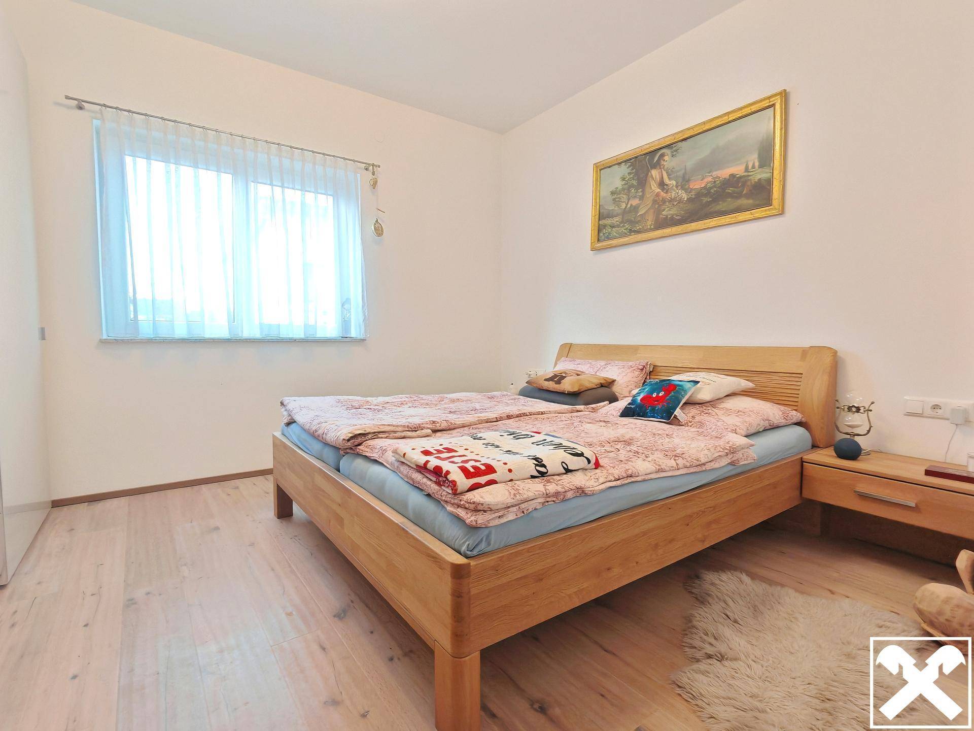 Helles Schlafzimmer mit Holzbett, Nachttisch und hellem Holzboden.