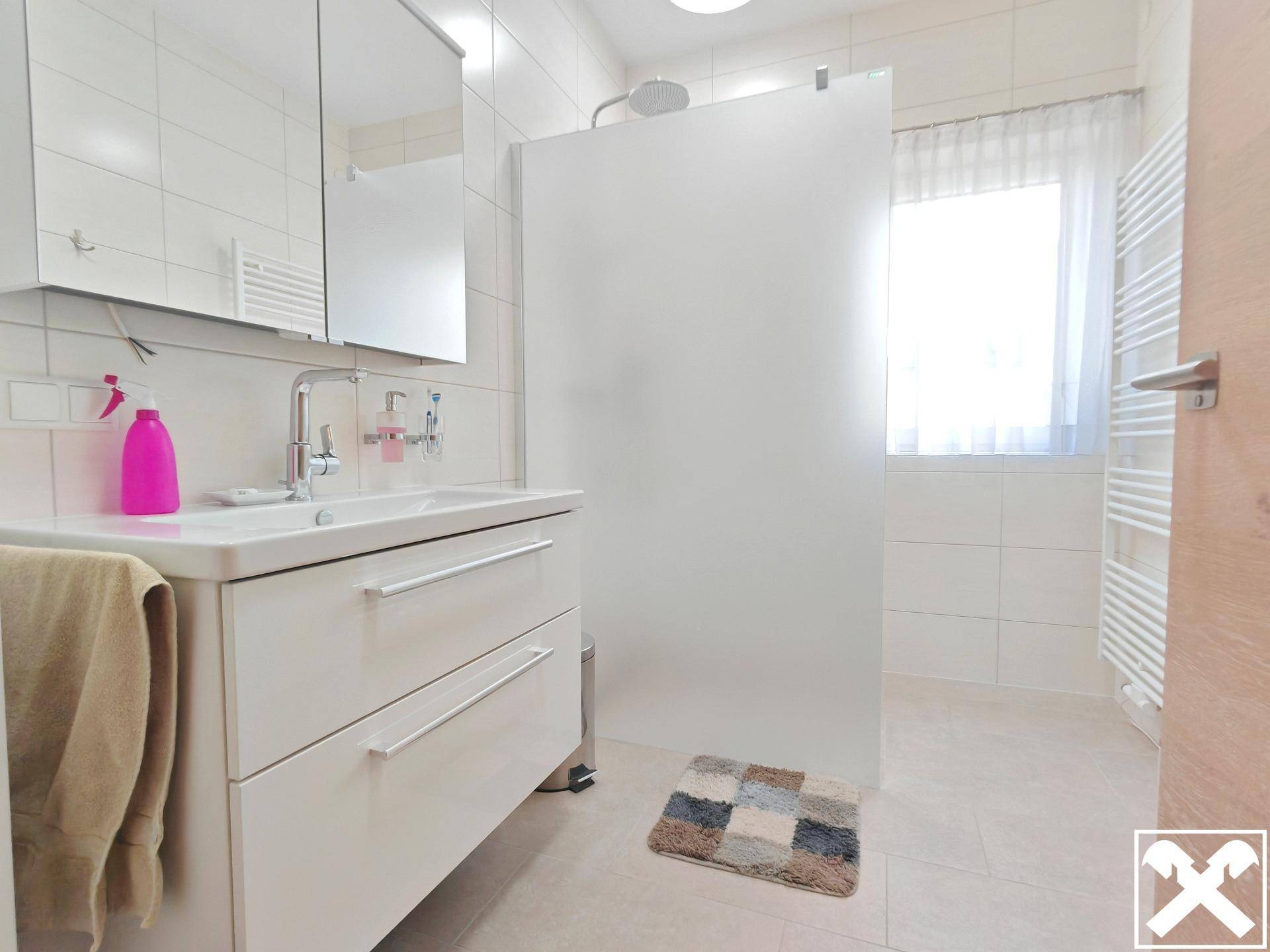 Modernes Badezimmer mit großer Dusche, Einzelwaschbecken und beheiztem Handtuchhalter.