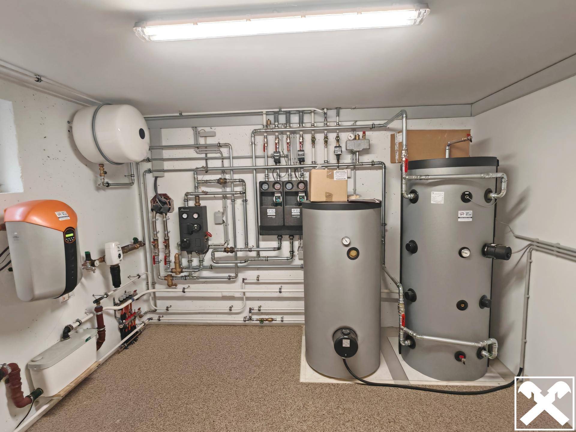 Heizungsraum mit komplexen Rohrleitungen, Warmwasserspeichern und Steuerungseinheiten.