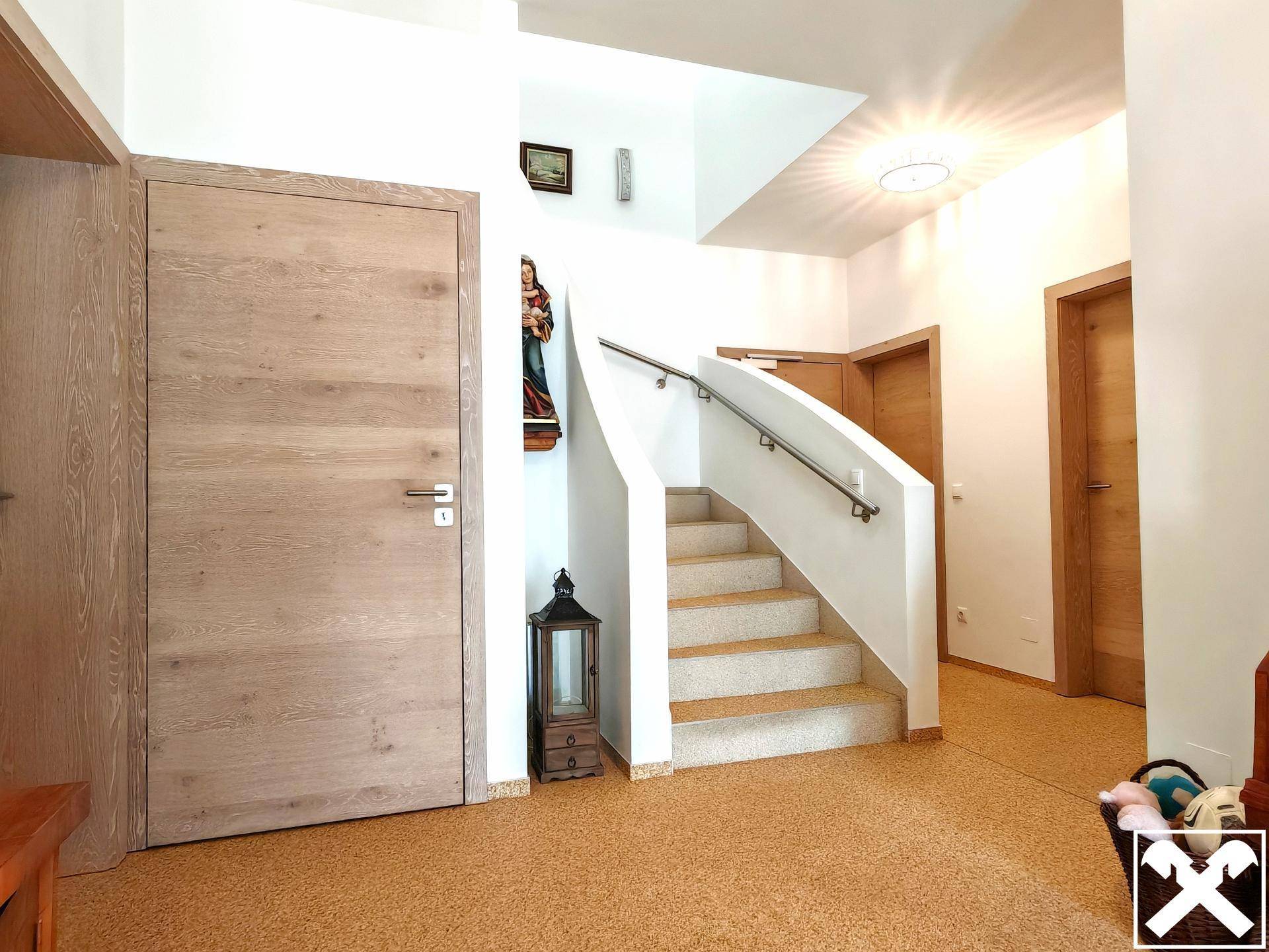 Heller Eingangsbereich mit Holztreppe, Handlauf und Korkboden.