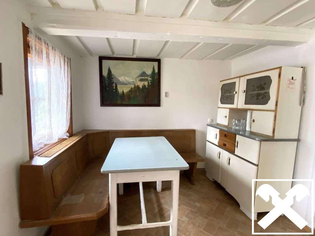 Essbereich mit traditioneller Eckbank, Holztisch und einem alten Küchenschrank.