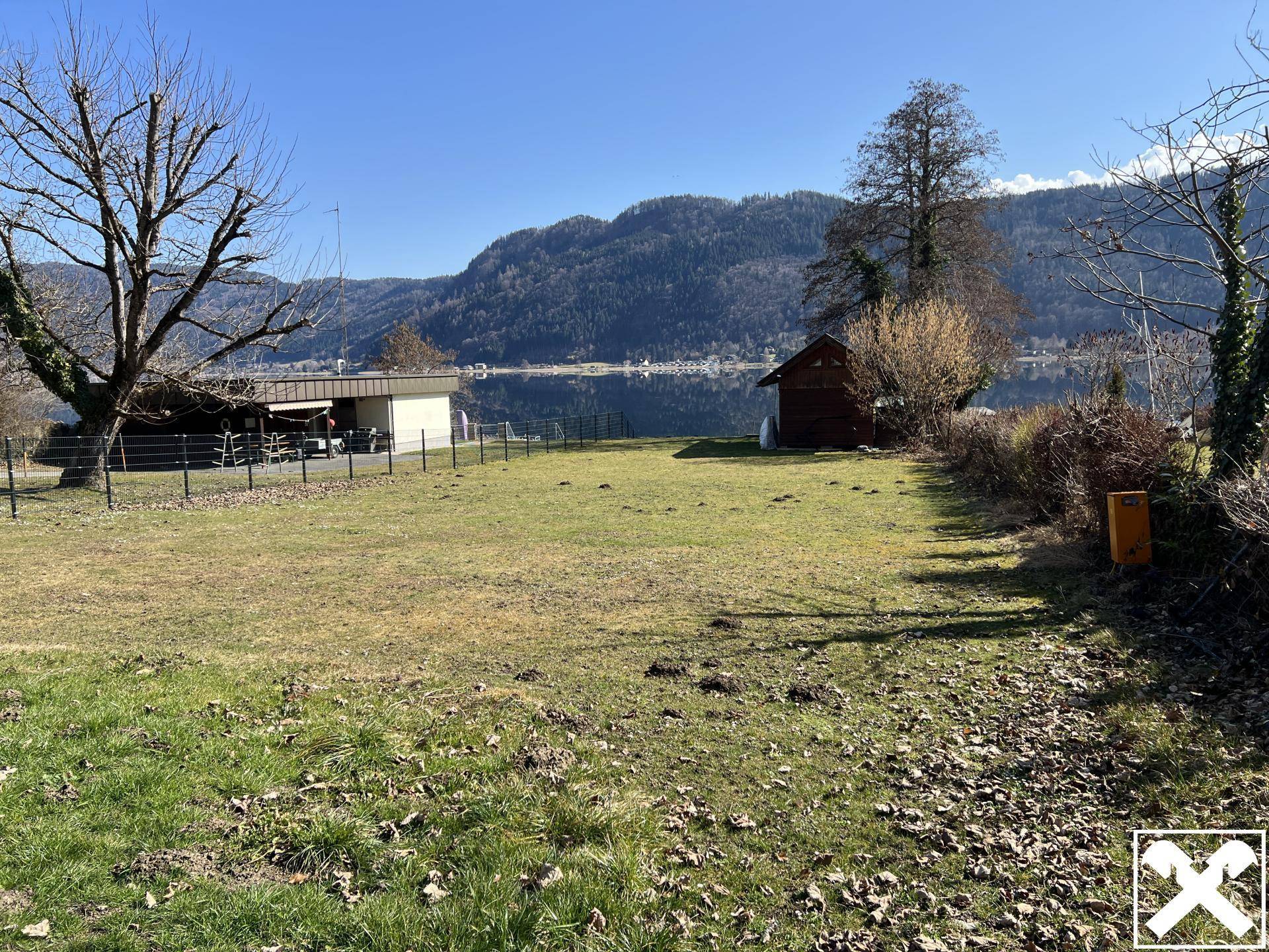 Weitläufige Rasenfläche mit Blick auf den See und die umliegende Berglandschaft.