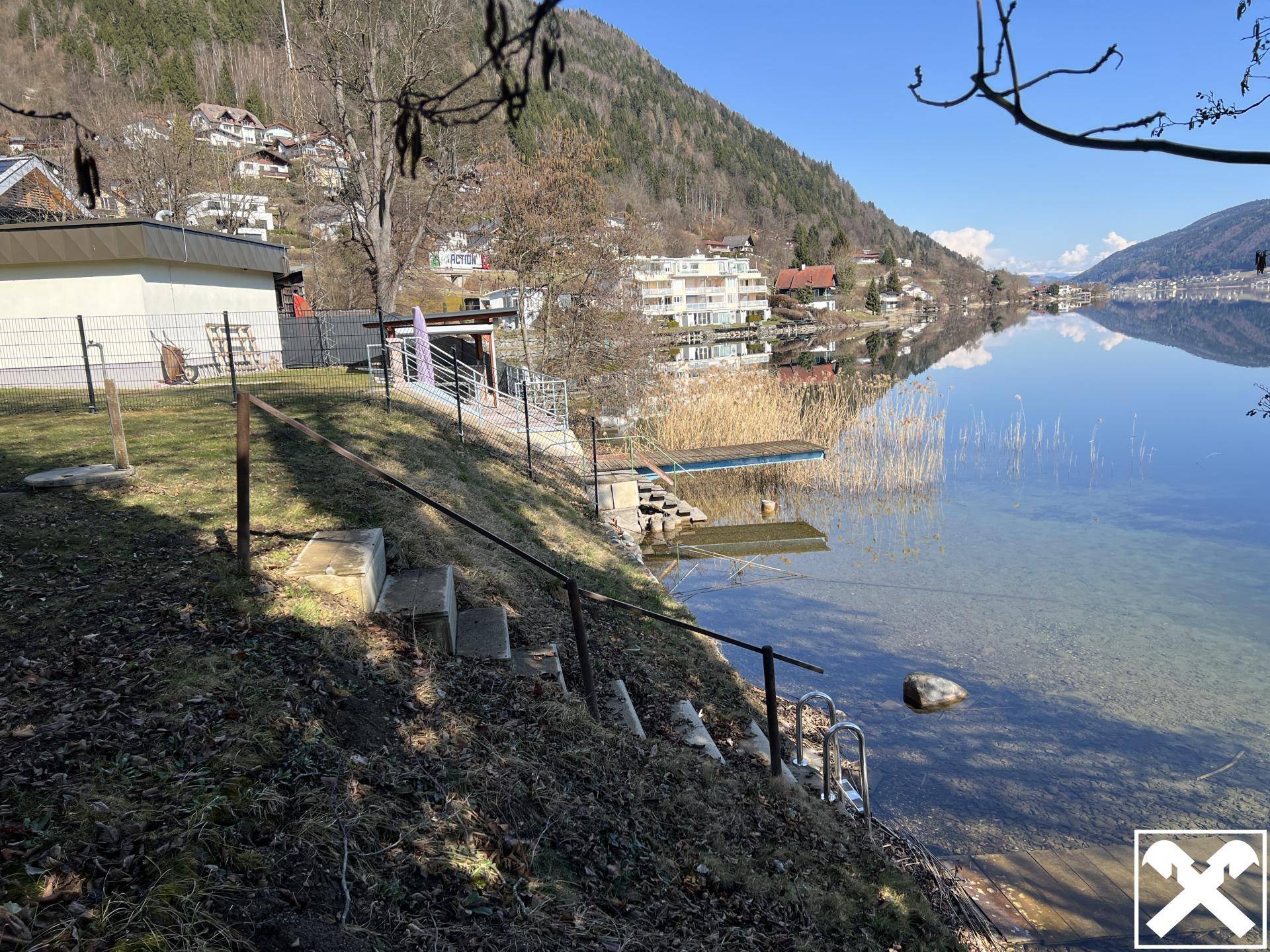 Seezugang mit Treppe und Sprungbrett, umgeben von Häusern am Ufer.