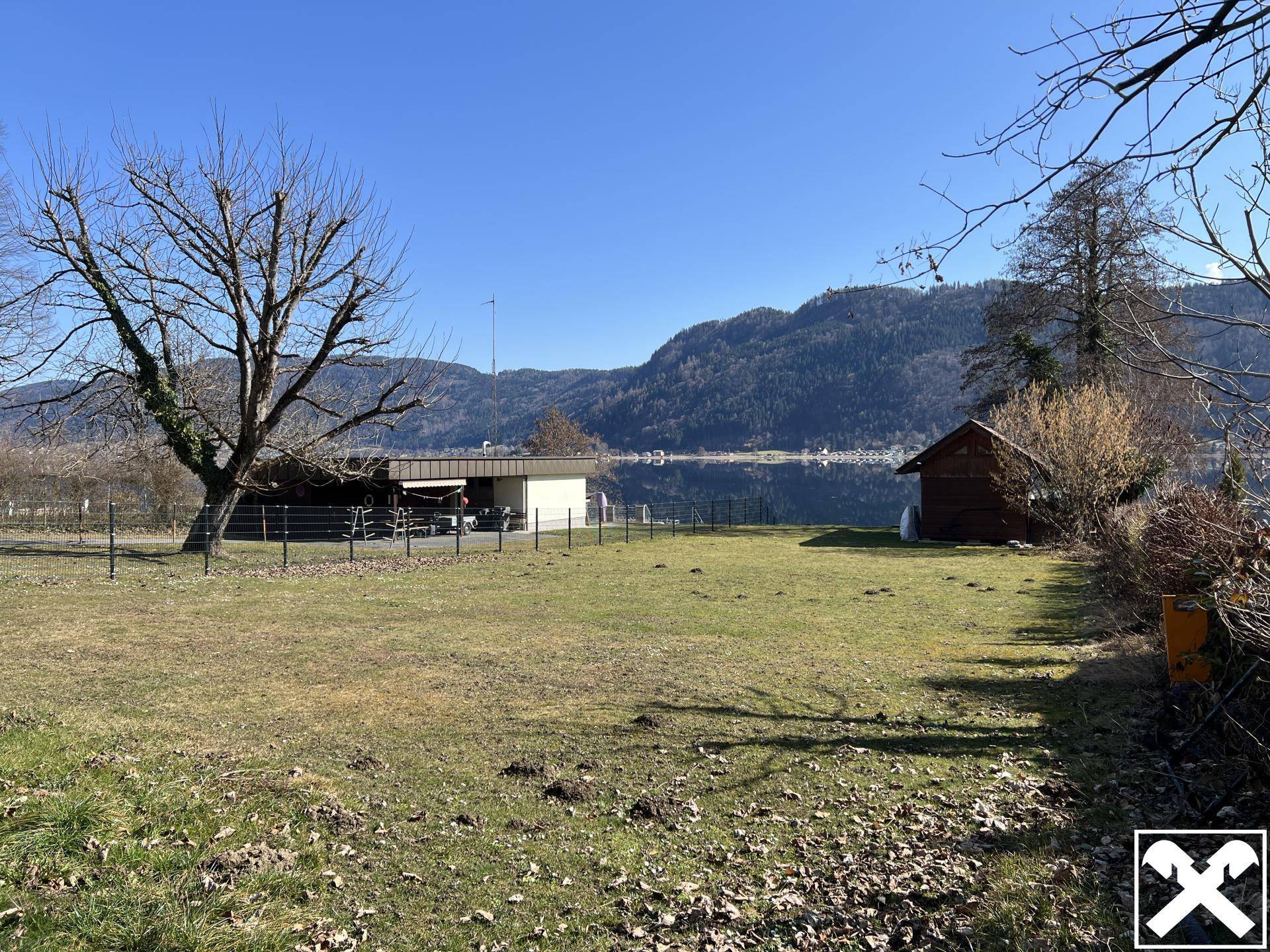 Weitläufige Rasenfläche mit Blick auf den See und die umliegende Berglandschaft.