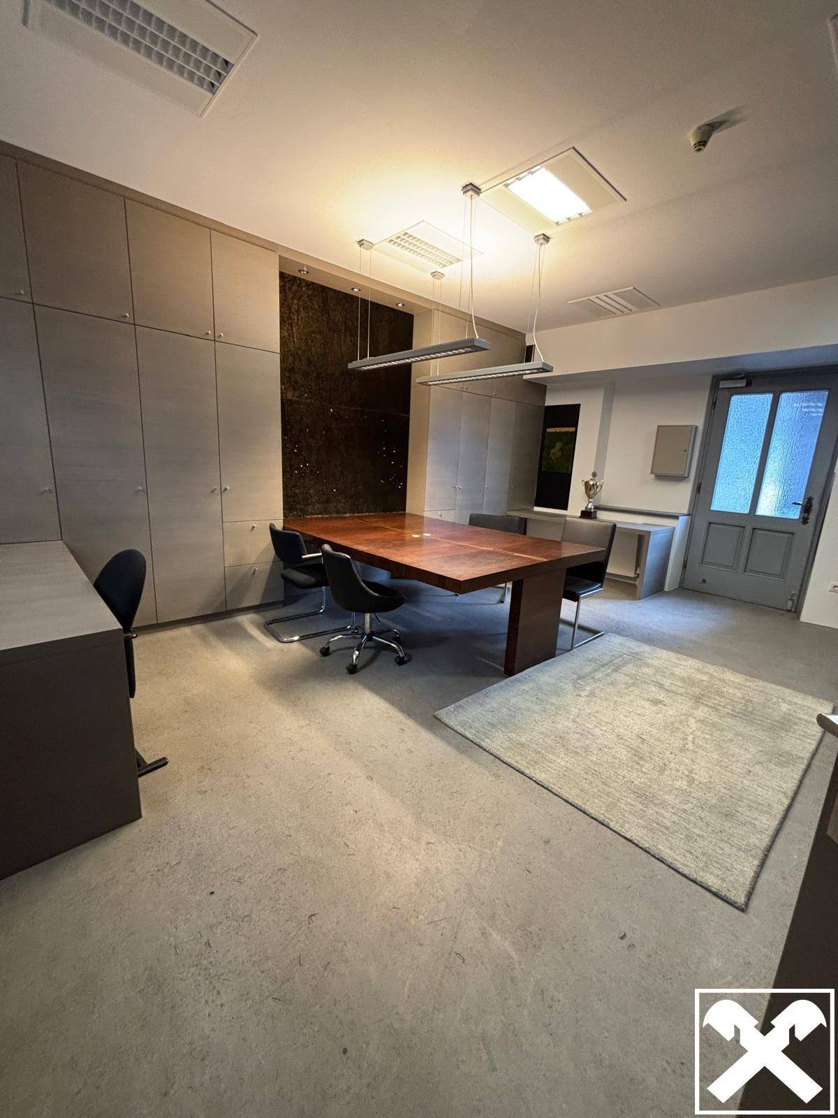 Modernes Büro oder Konferenzraum mit großem Holztisch, Einbauschränken und Betonboden.