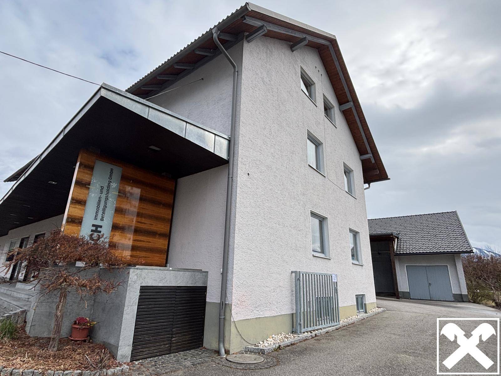 Seitenansicht eines Gebäudes mit einer Garage und einem modernen Eingangsbereich mit Holzverkleidung.