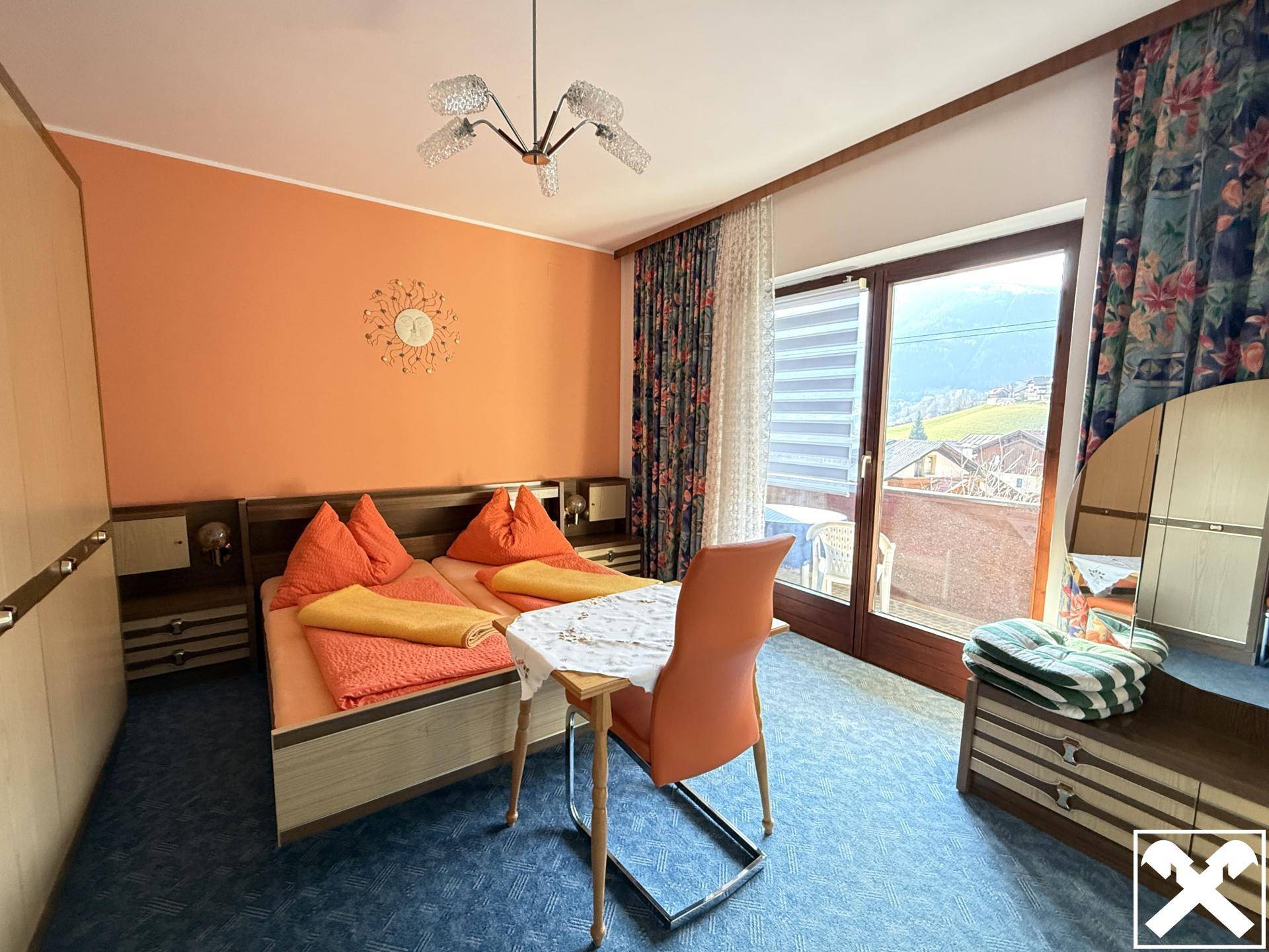 Schlafzimmer mit orangefarbenen Wänden, blauer Teppichboden und Zugang zu einem Balkon.