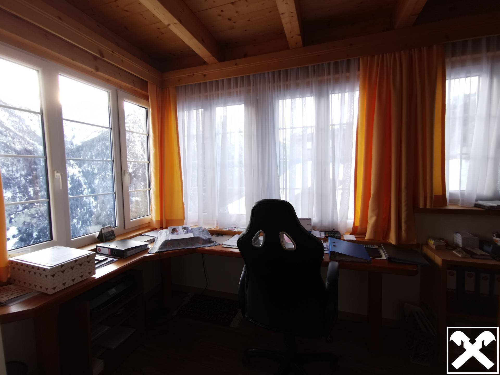 Helles Büro mit Eckschreibtisch und großen Fenstern, die einen weiten Blick auf die verschneite Landschaft bieten.
